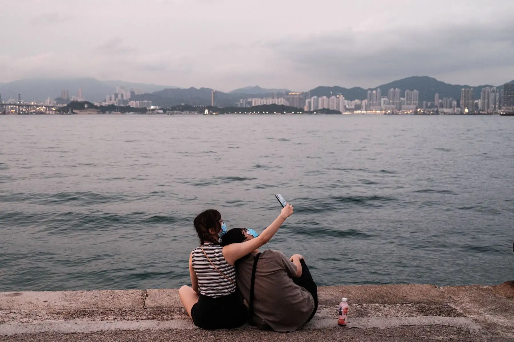 Una pareja con máscaras faciales, como medida de precaución contra el coronavirus COVID-19, se toma un selfie en un muelle de carga denominado 