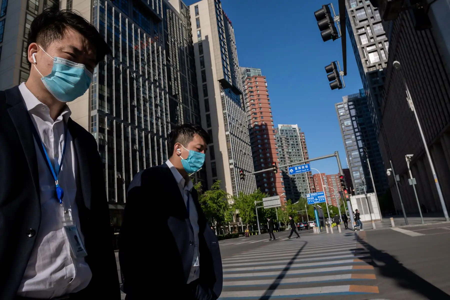 Personas con máscaras faciales en medio de las preocupaciones por el coronavirus COVID-19 caminan por una calle en Beijing. Foto: AFP