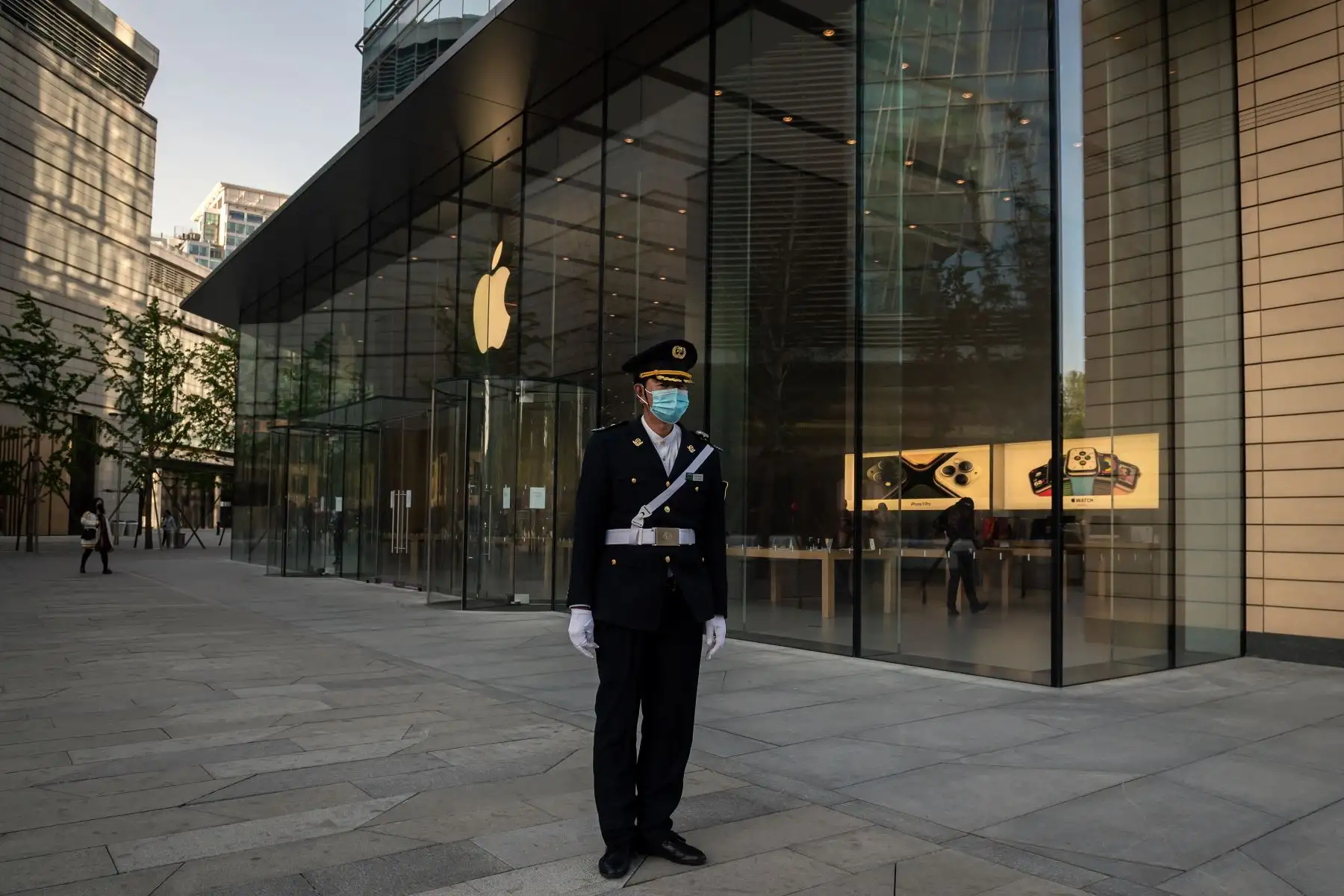 Un guardia de seguridad con una máscara facial contra el coronavirus COVID-19 asegura un área fuera de una tienda de Apple (atrás) afuera de un centro comercial en Beijing. Foto: AFP