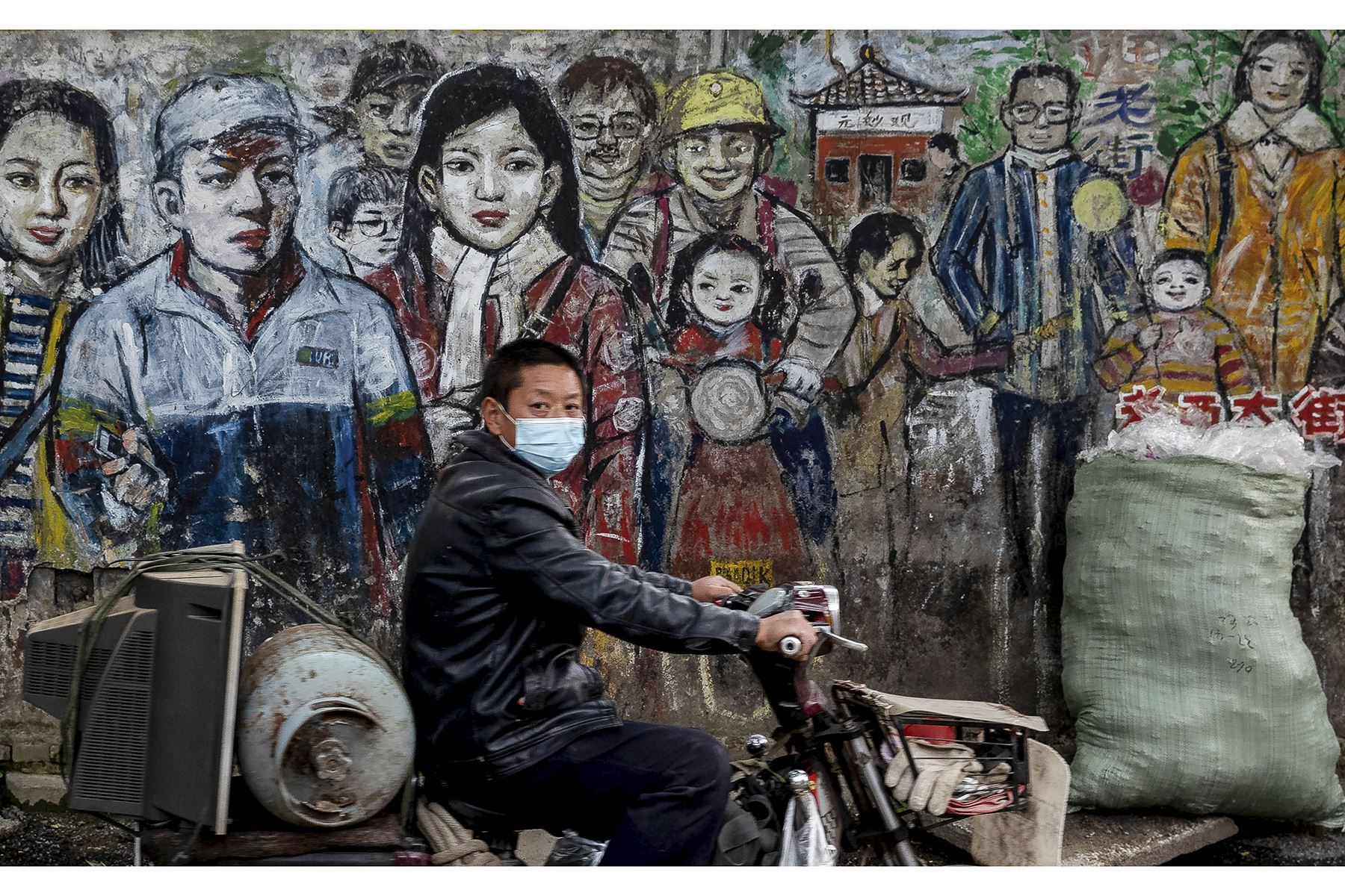 Hombre protegido con máscara facial contra el coronavirus conduce su motocicleta por una calle en Wuhan, en la provincia central de Hubei, China. Foto: AFP