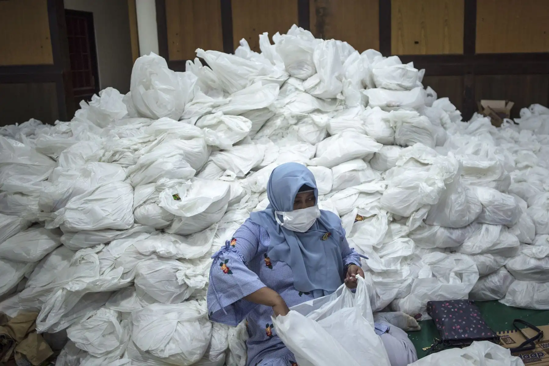 Una mujer prepara paquetes de necesidades básicas para distribuir a las personas afectadas por el coronavirus, en Surabaya. Foto: AFP