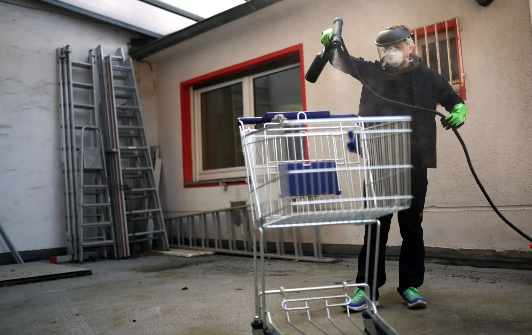 Un estudiante desinfecta su carrito de compras con alcohol en Colonia, Alemania. Foto: AFP
