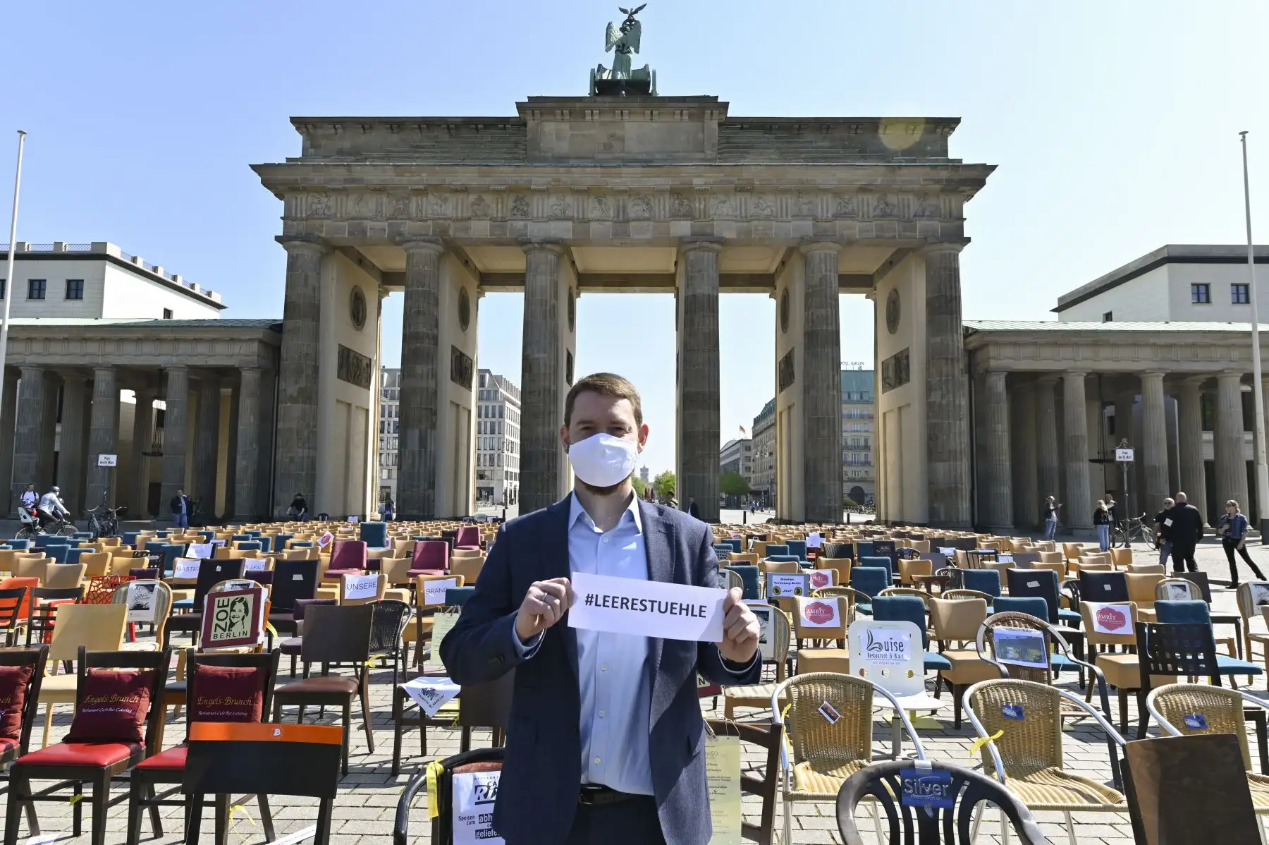 Erich Nagl, miembro de la red de gastrónomos Leaders Club, posa con una pancarta que dice "sillas vacías" frente a filas con sillas vacías colocadas frente a la histórica Puerta de Brandenburgo de Berlí durante una protesta de gastrónomos en medio de la pandemia del nuevo coronavirus COVID-19. Foto: AFP