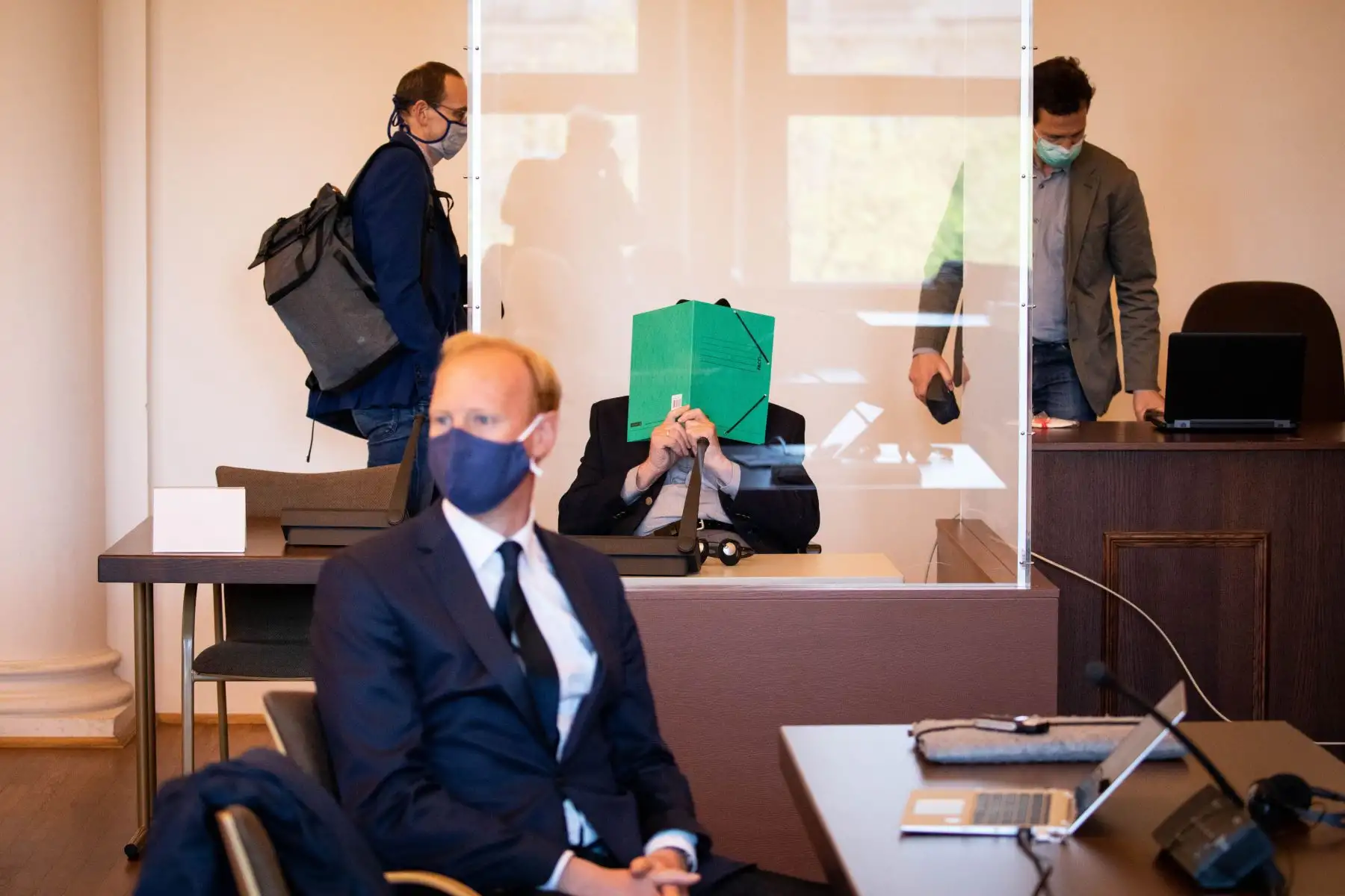Bruno Dey, un ex vigilante de las SS en el campo de concentración de Stutthof, se cubre la cara y se sienta en una silla de ruedas junto a su abogado en una sala del tribunal antes de una audiencia en Hamburgo. Foto: AFP