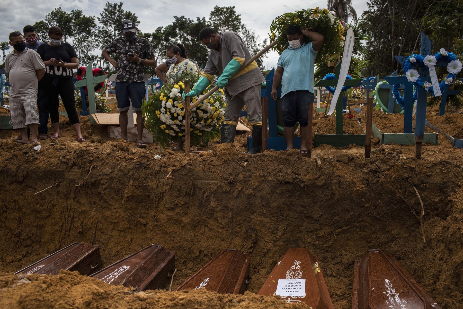 Sepultureros trabajan este martes en un entierro colectivo en el cementerio Nossa Senhora Aparecida mientras familiares despiden a sus seres queridos, en la ciudad de Manaos, estado Amazonas (Brasil). Foto: EFE