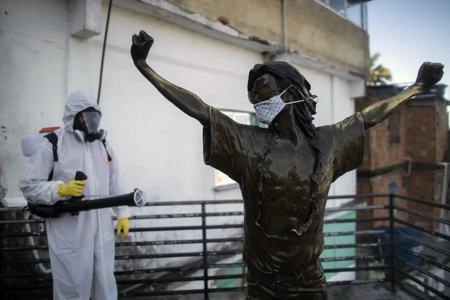Un voluntario desinfecta la estatua del cantante estadounidense Michael Jackson, en la favela de Santa Marta en Río de Janeiro, Brasil, durante la pandemia del coronavirus COVID-19. Foto: AFP