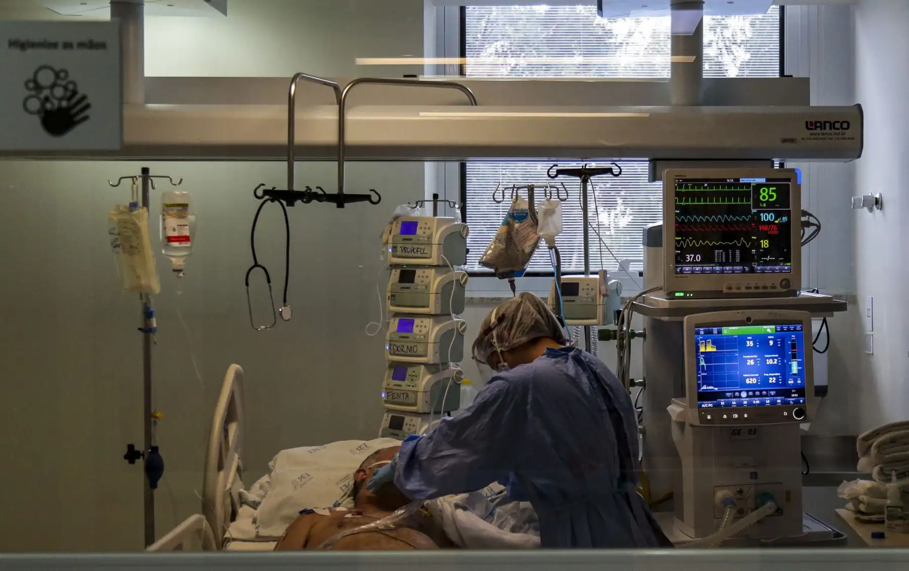 Un trabajador de la salud con un traje de bioseguridad revisa a un paciente COVID-19 en la unidad de cuidados intensivos, en el hospital Emilio Ribas en Sao Paulo. Foto: AFP