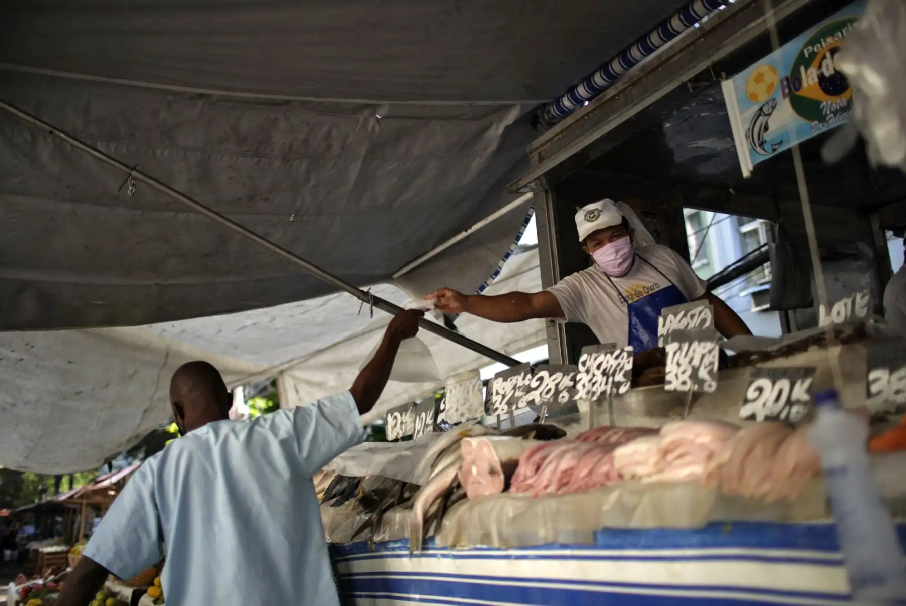 Un hombre usa una máscara facial mientras vende pescado después de que los mercados callejeros se reabrieron en Río de Janeiro. Foto: AFP