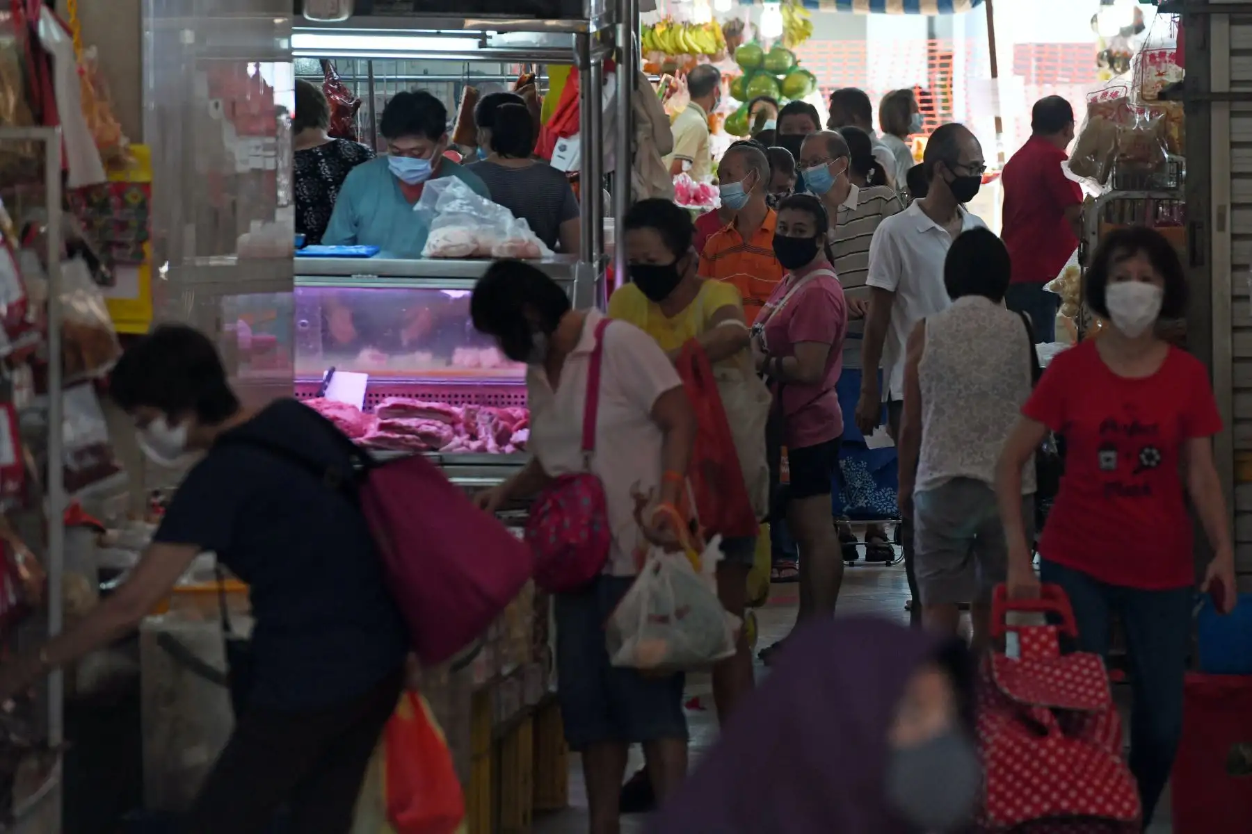 Personas que usan mascarillas como medida de prevención contra la propagación de la tienda de coronavirus COVID-19 en un concurrido mercado húmedo en Singapur. Foto: AFP