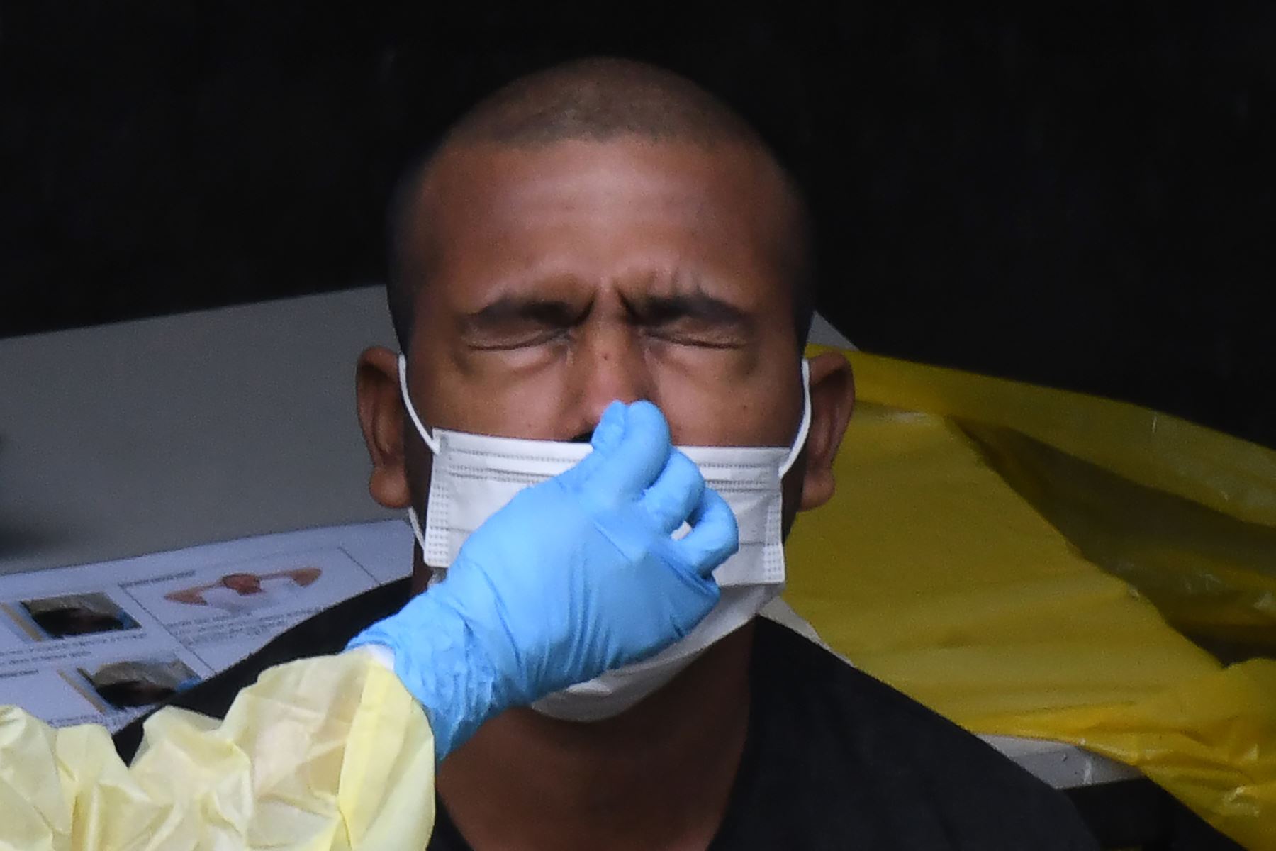 Un trabajador de la salud vestido con equipo de protección personal recolecta una muestra de hisopo nasal de un trabajador migrante para la prueba del nuevo coronavirus COVID-19. Foto: AFP