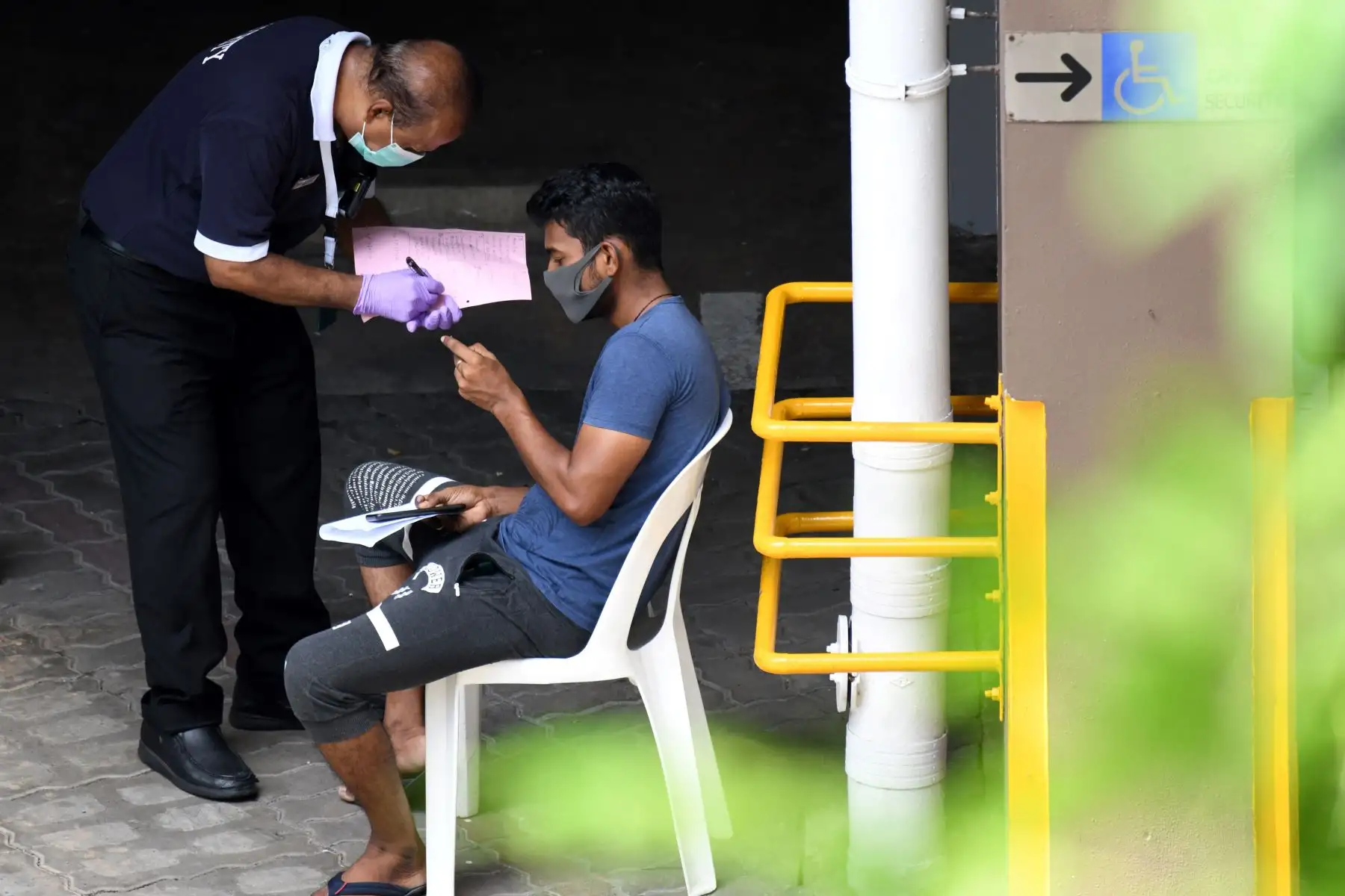 Un guardia de seguridad elimina los detalles de un trabajador migrante antes de someterse a un chequeo médico para detectar el nuevo coronavirus COVID-19 en un dormitorio de trabajadores extranjeros. Foto: AFP