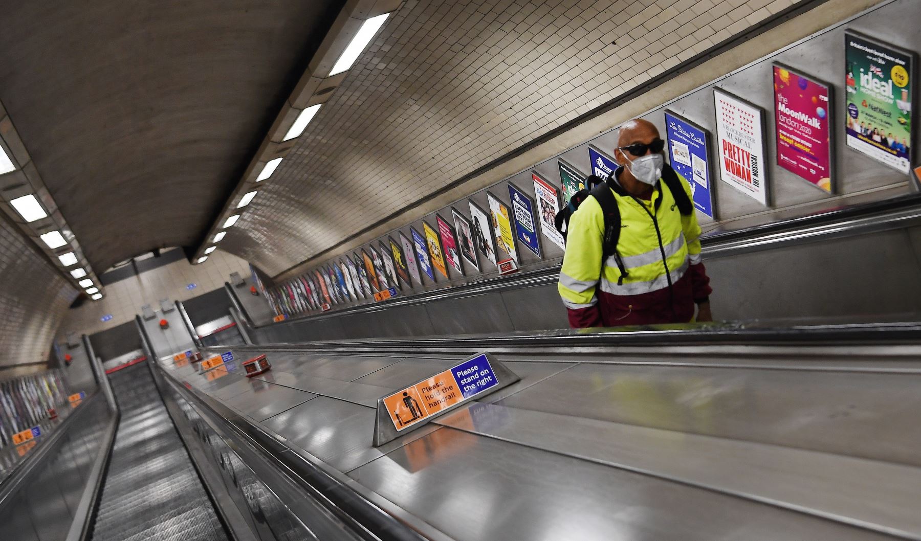 Un viajero solitario, con una máscara facial, sube una escalera mecánica en una estación de metro en Londres, Gran Bretaña. Foto: EFE