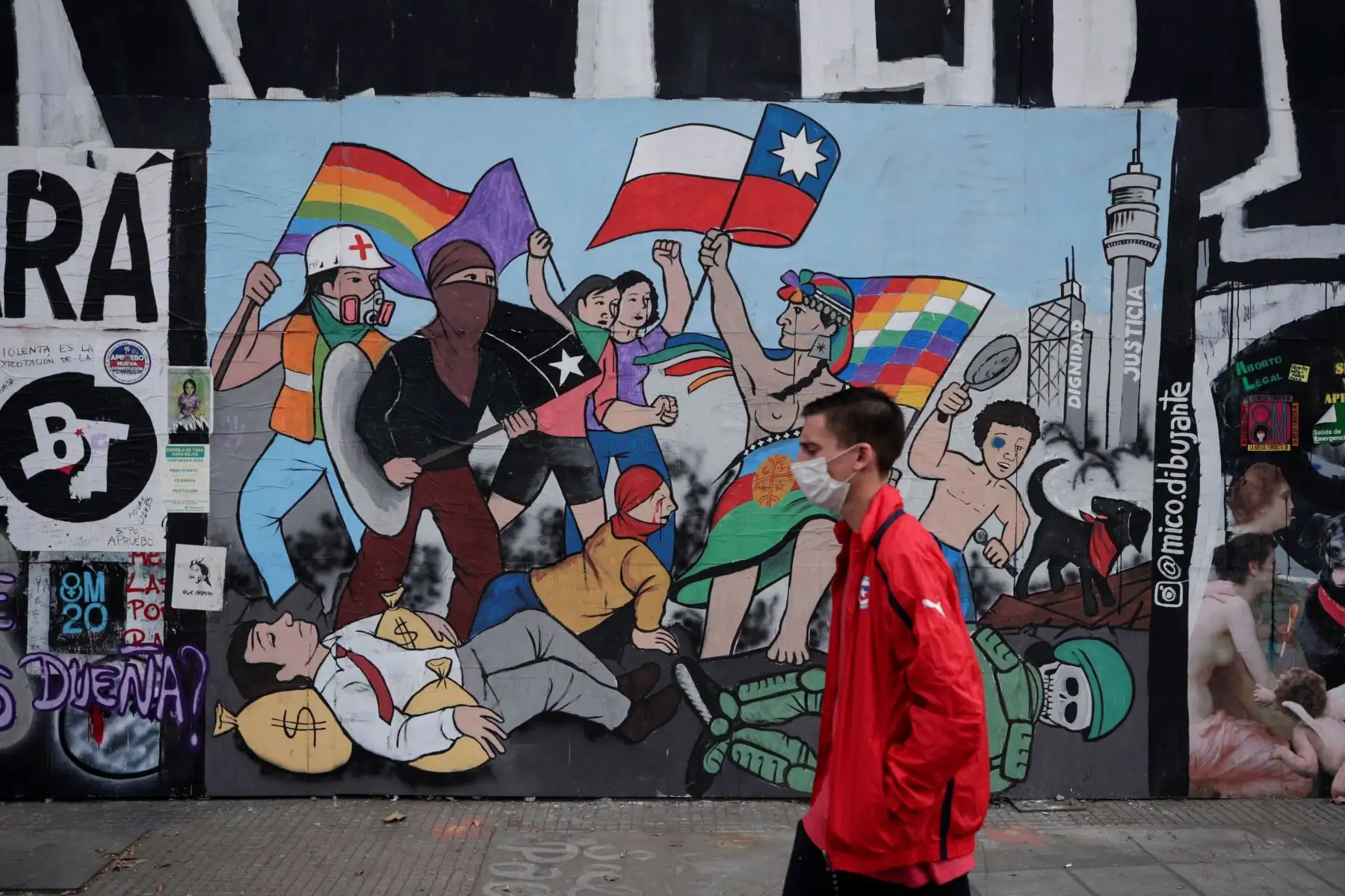 Un hombre camina frente a un graffitti en una de las calles de Santiago de Chile. Foto: EFE
