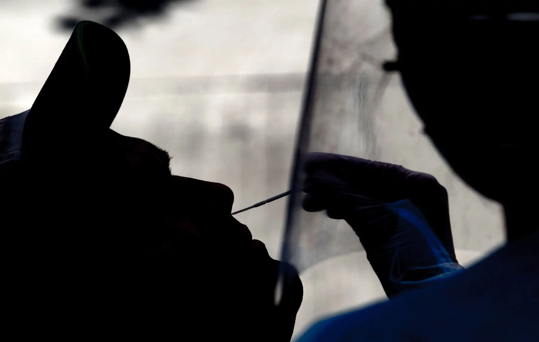 Un trabajador de salud recolecta una muestra de hisopo nasal de un hombre en un automóvil para analizar el COVID-19 en una estación de servicio en Santiago. Foto: AFP