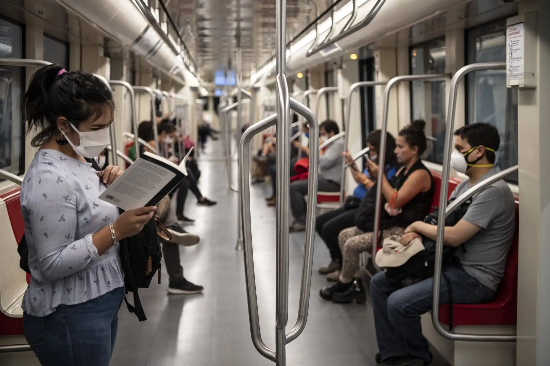 Un viajero usa una máscara facial como medida de precaución contra la propagación del nuevo coronavirus, COVID-19, mientras lee un libro en el metro de Santiago. Foto: AFP