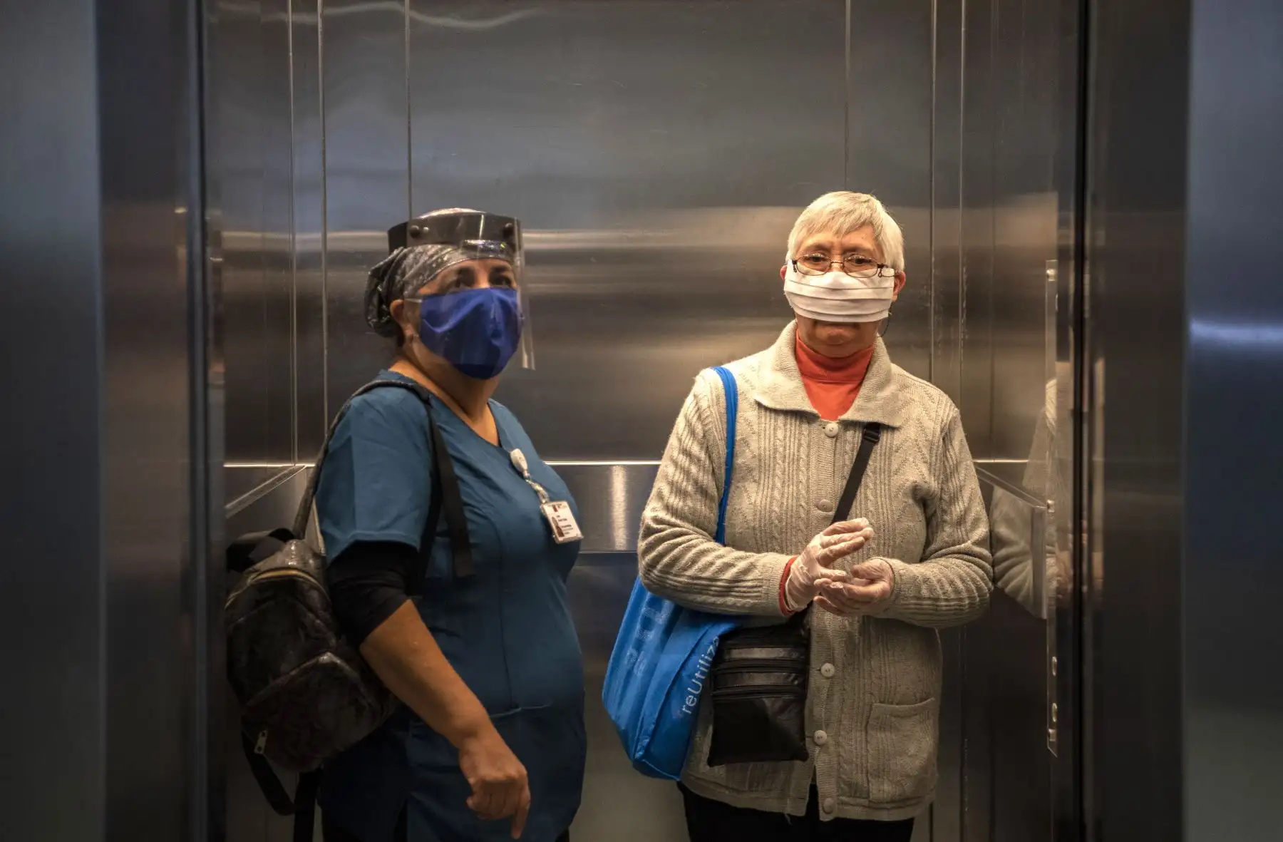 Una enfermera y un paciente usan máscaras faciales mientras permanecen en un elevador en el Hospital Del Carmen en Santiago. Foto: AFP