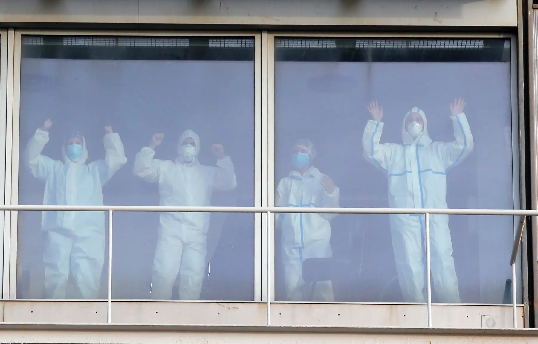 Los trabajadores de la salud con trajes protectores en el Hospital del Mar de Barcelona, alientan a las personas que hacen ejercicio al aire libre. Foto: AFP