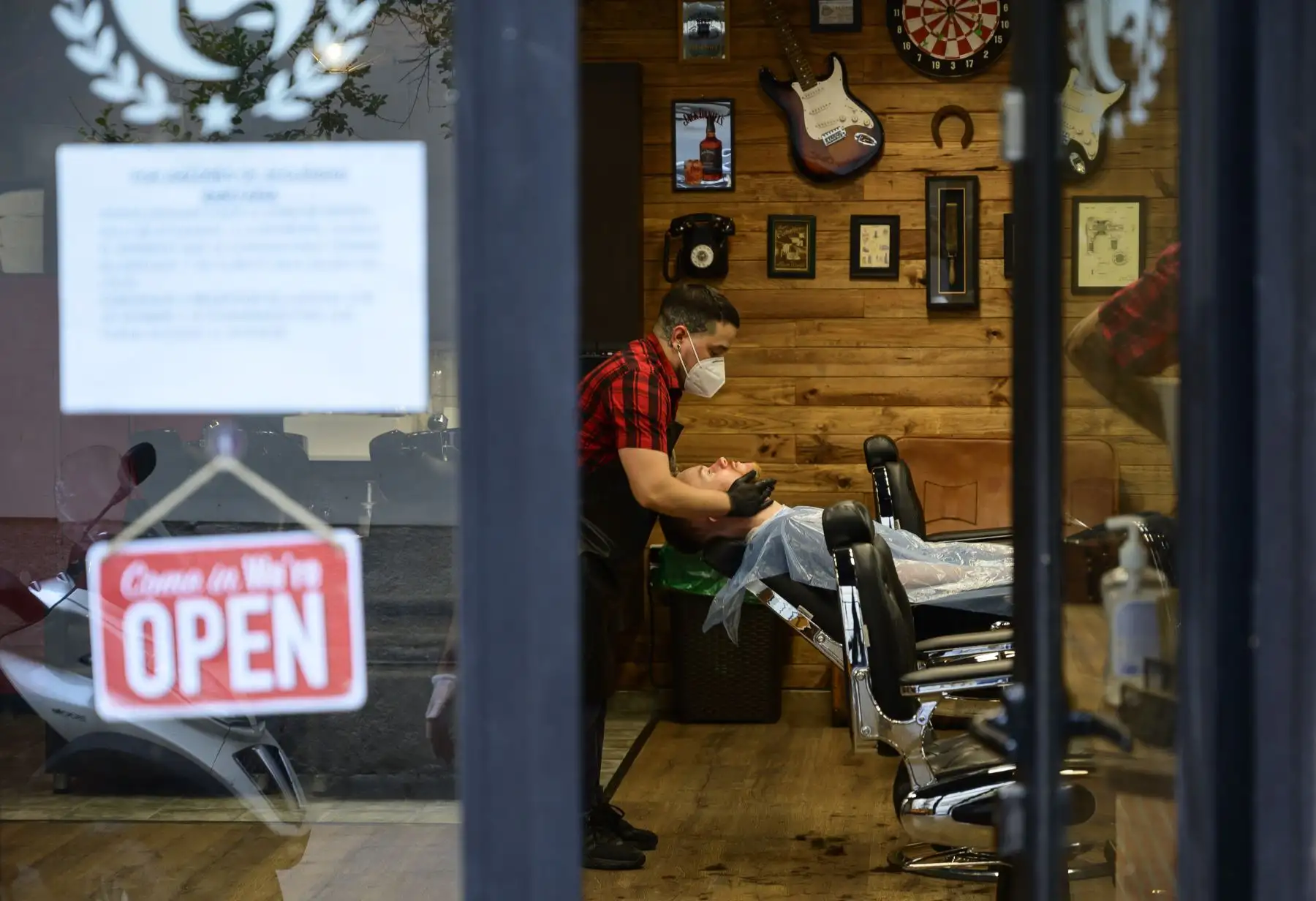 Un peluquero atiende a un cliente después de reabrir su barbería en Madrid. Foto: AFP