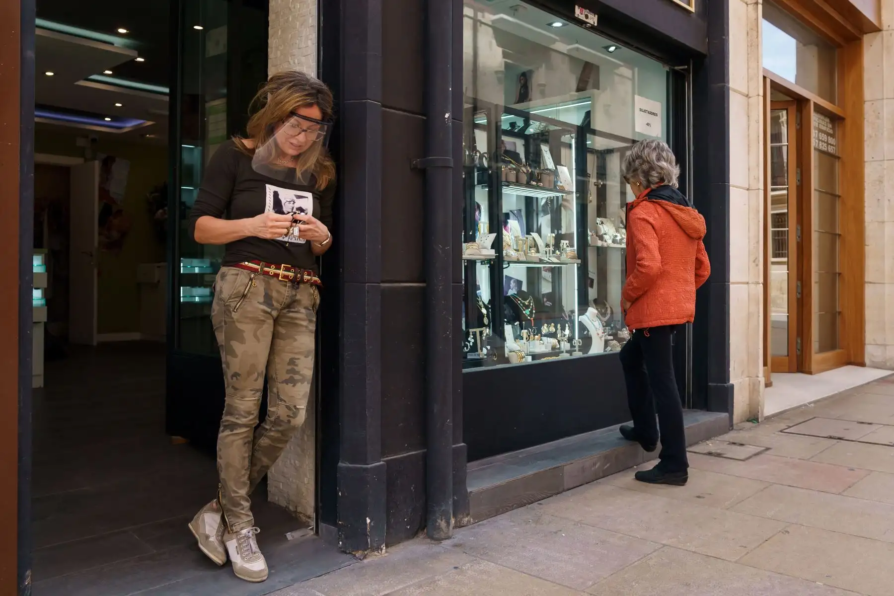 Una mujer mira la ventana de un joyero mientras la dueña, Emma, espera en la puerta al primer cliente, en Burgos, el 4 de mayo de 2020, después de reabrir por primera vez desde el inicio de un cierre nacional para evitar la propagación del Enfermedad de COVID-19. Foto: AFP