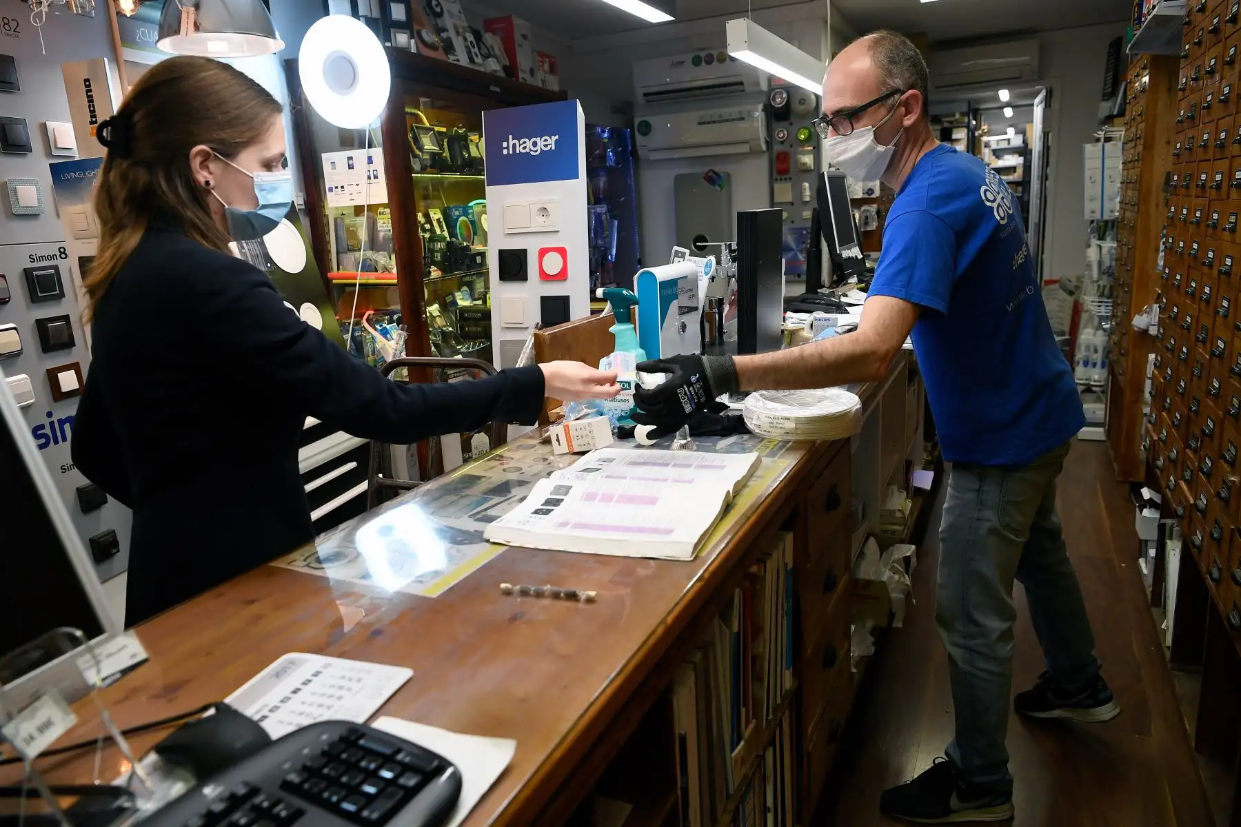 Un asistente de tienda atiende a un cliente en una tienda de suministros eléctricos en Barcelona. Foto: AFP