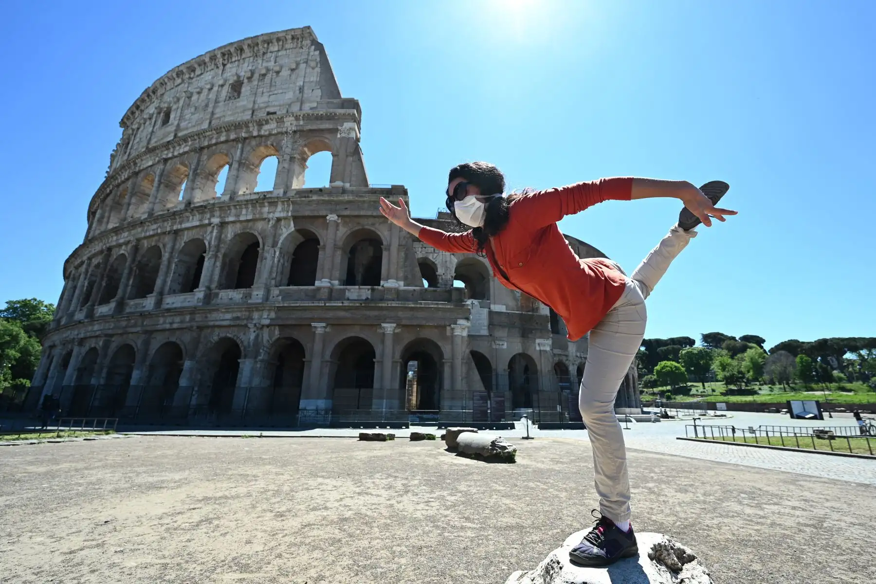 Una mujer mantiene una postura de yoga mientras se ejercita en el monumento del Coliseo en Roma. Foto: AFP