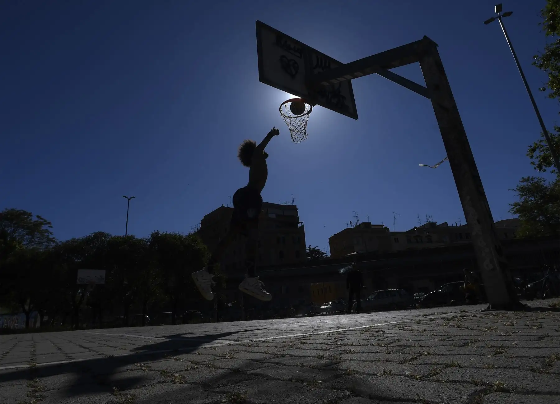 Un joven juega baloncesto en un parque el 4 de mayo de 2020 en Roma cuando Italia comienza a aliviar su confinamiento. Foto: AFP
