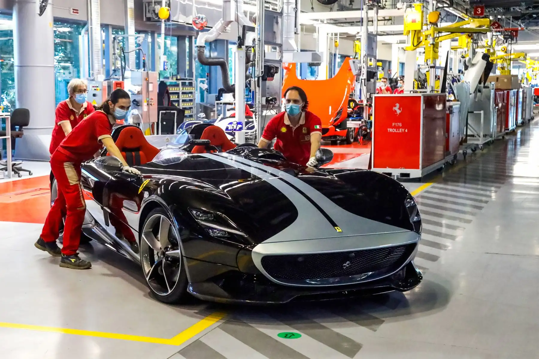 Esta foto tomada y entregada por el fabricante italiano de autos deportivos de lujo Ferrari muestra a los trabajadores empujando un auto deportivo de dos plazas, mientras se reanuda la producción en la línea de ensamblaje. Foto: AFP