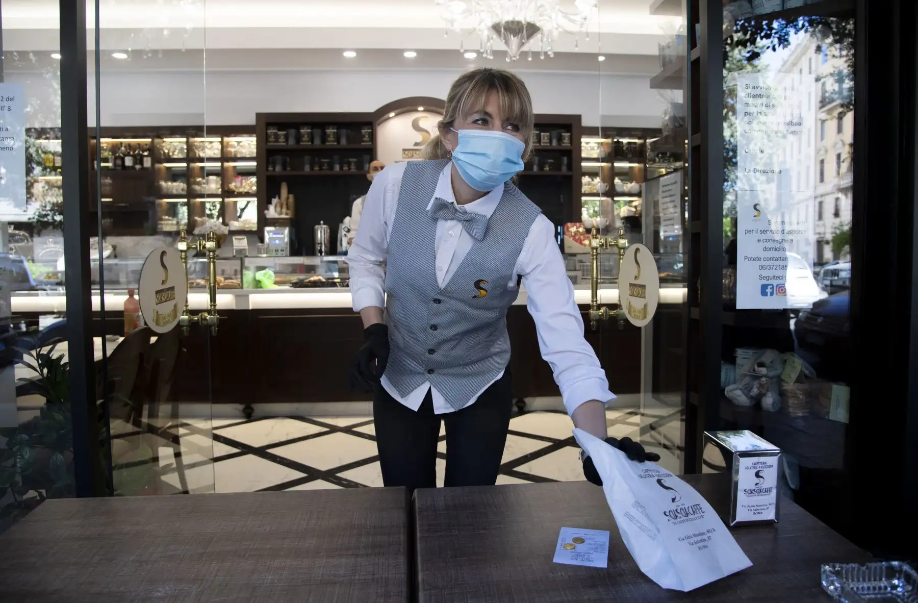Una camarera le entrega un paquete de comida para llevar a un cliente en el Sciascia Caffe en Roma. Foto: AFP