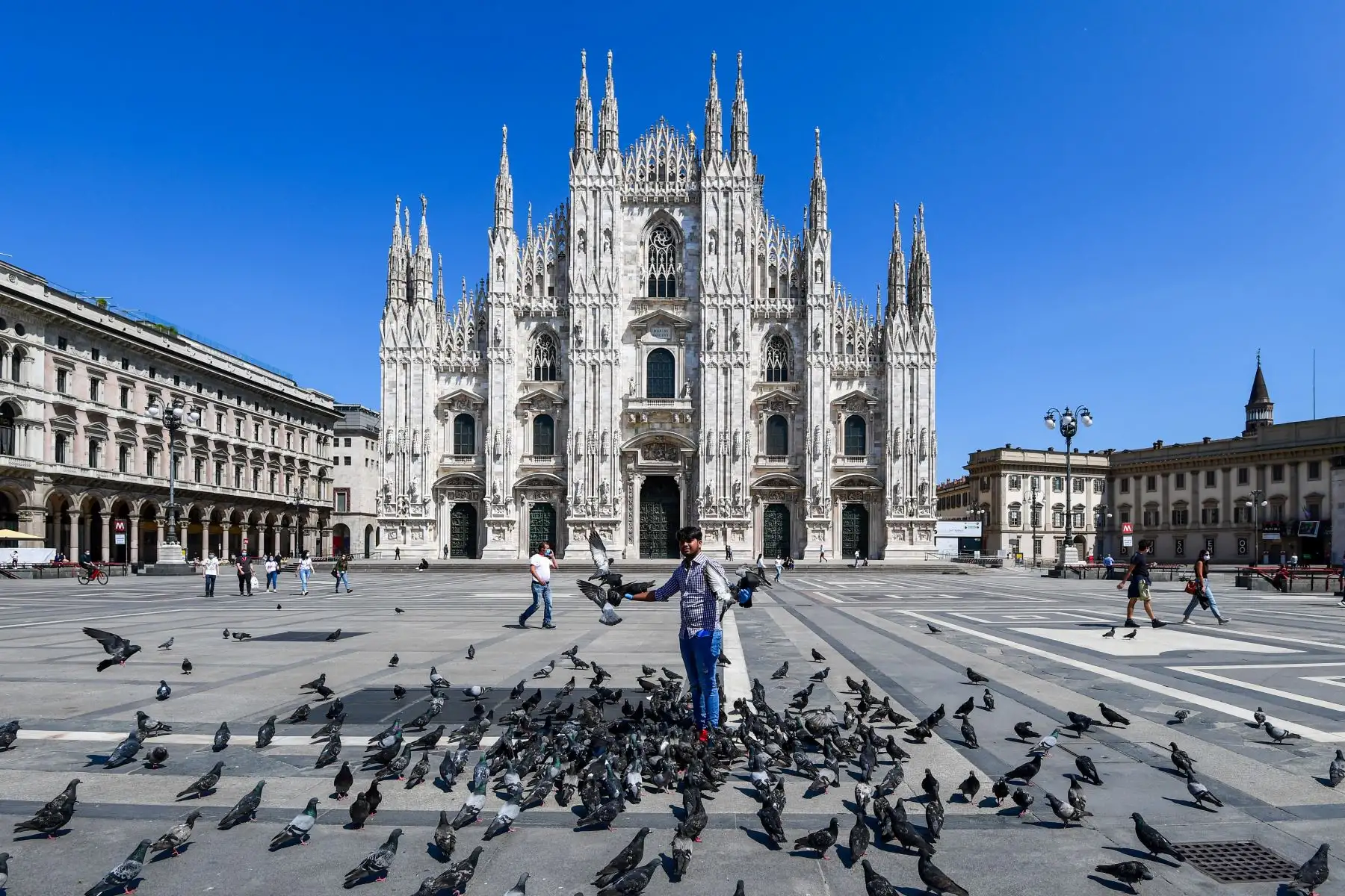 Un hombre alimenta palomas en la Piazza del Duomo, en el centro de Milán. Foto: AFP