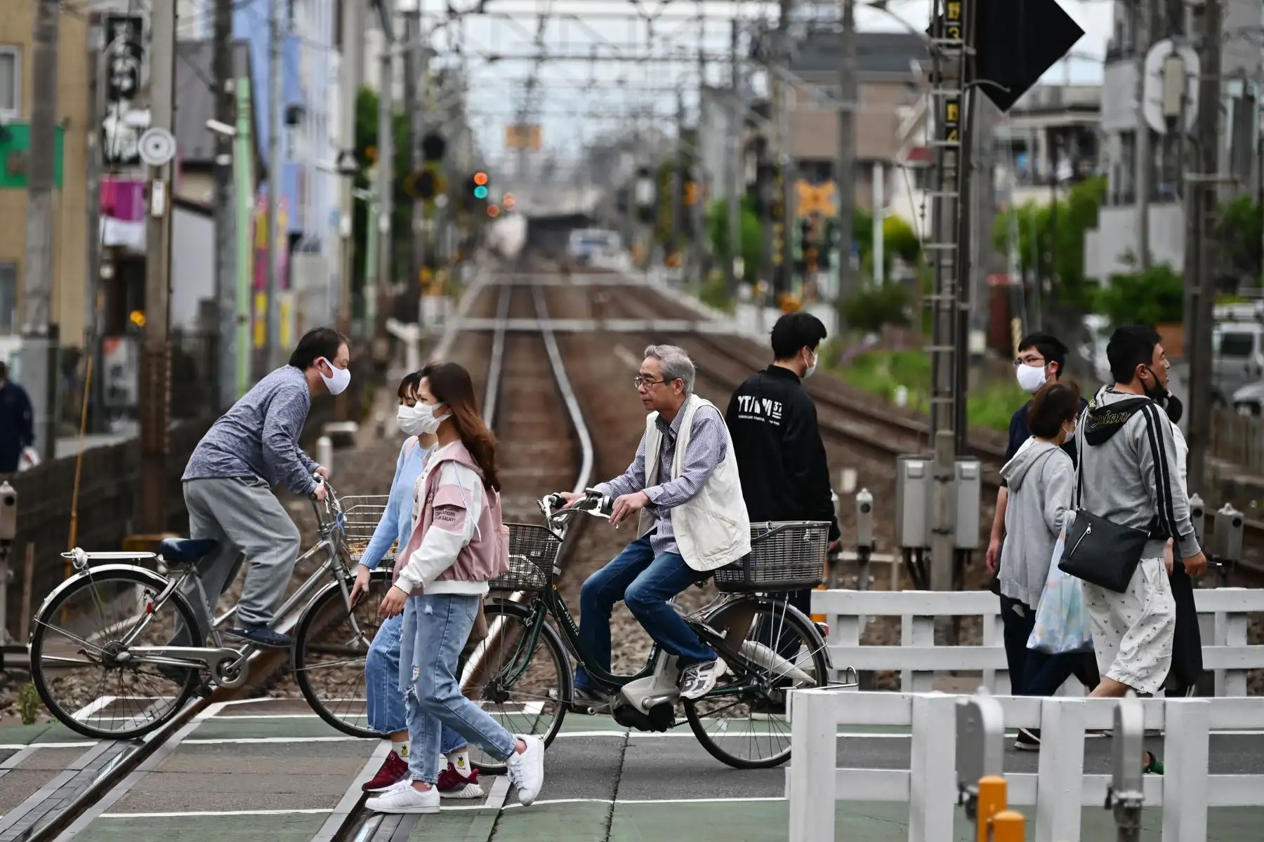 La gente cruza las vías del ferrocarril en una zona residencial en Tokio. Foto: AFP