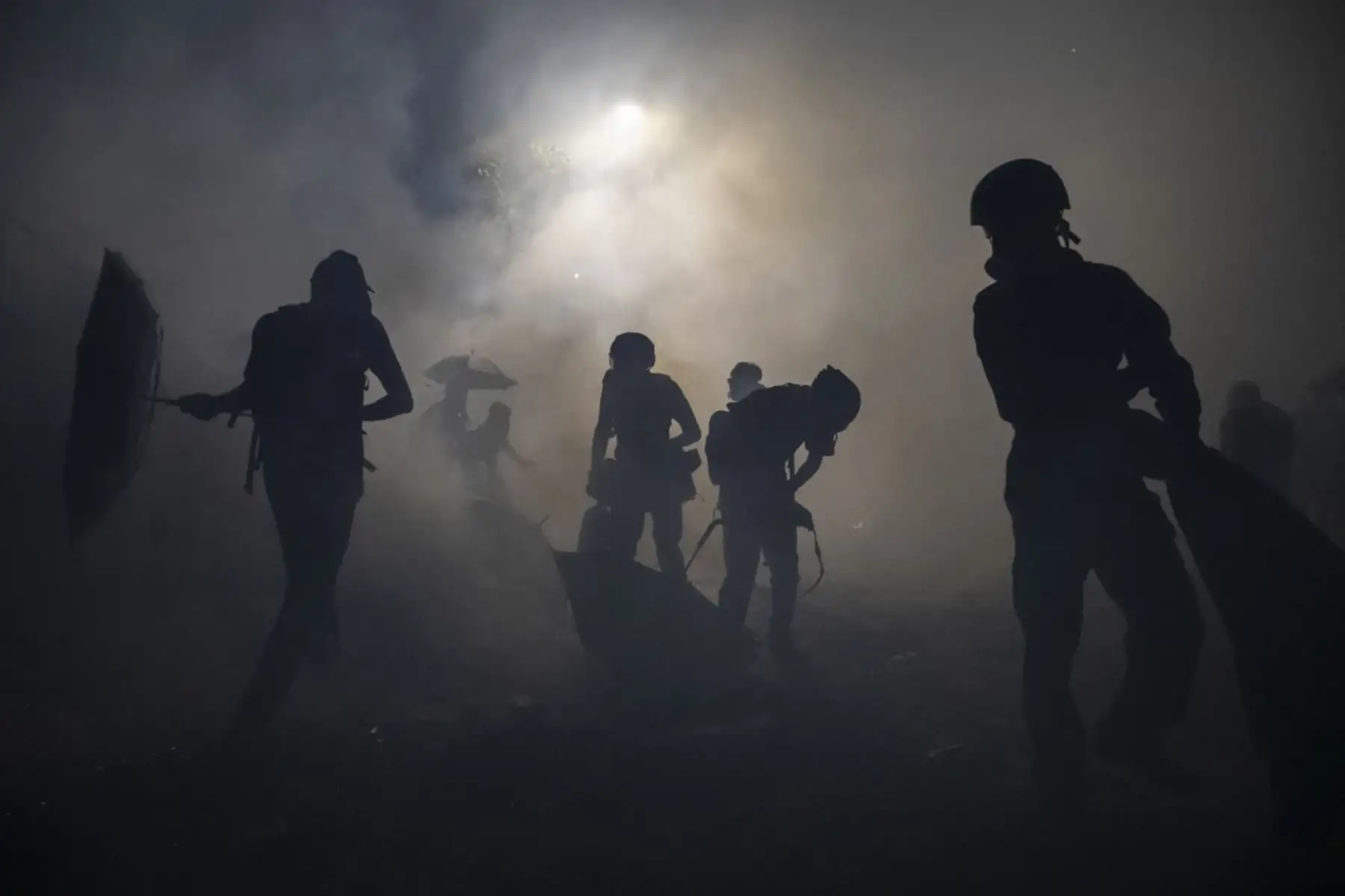 Los manifestantes antigubernamentales se paran en una nube de gases lacrimógenos desatados durante un enfrentamiento con la policía antidisturbios en la Universidad China de Hong Kong. Foto: Reuters/Pulitzer