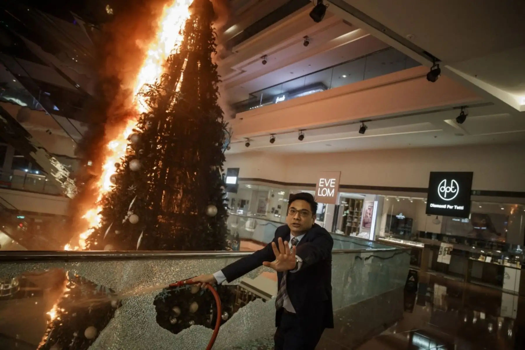 El personal de seguridad del centro comercial pide precaución mientras intenta apagar un árbol de Navidad en llamas en el centro comercial Festival Walk en Kowloon Tong, Hong Kong, China. Foto: Reuters/Pulitzer