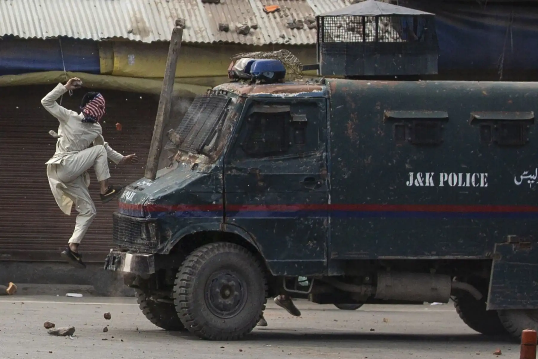 Un manifestante enmascarado Kashmir salta sobre el capó de un vehículo blindado de la policía india mientras le arroja piedras durante una protesta en Srinagar. Foto: AP/Pulitzer