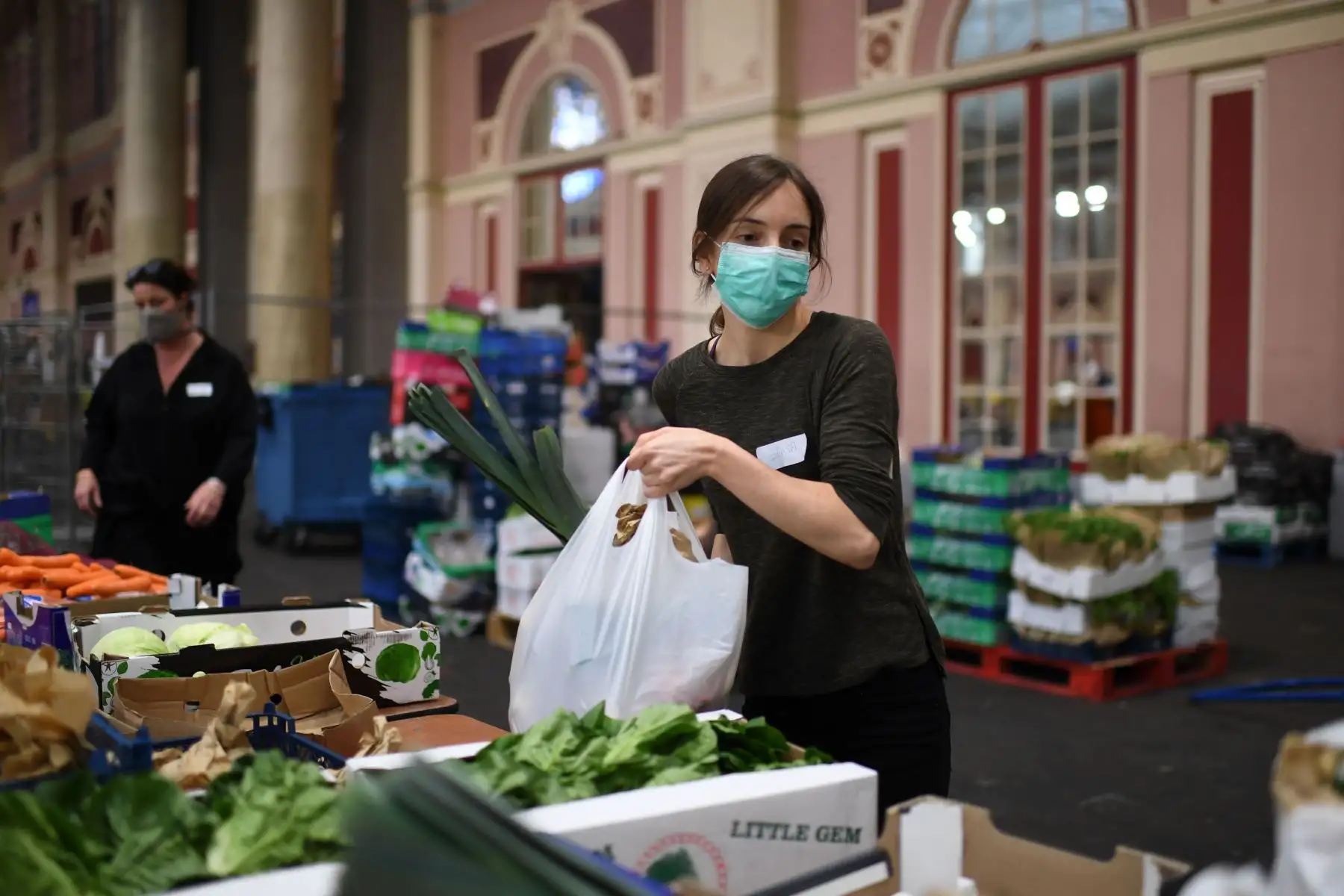 Los voluntarios que usan equipo de protección personal como medida de precaución contra COVID-19, trabajan para clasificar alimentos. Foto: AFP