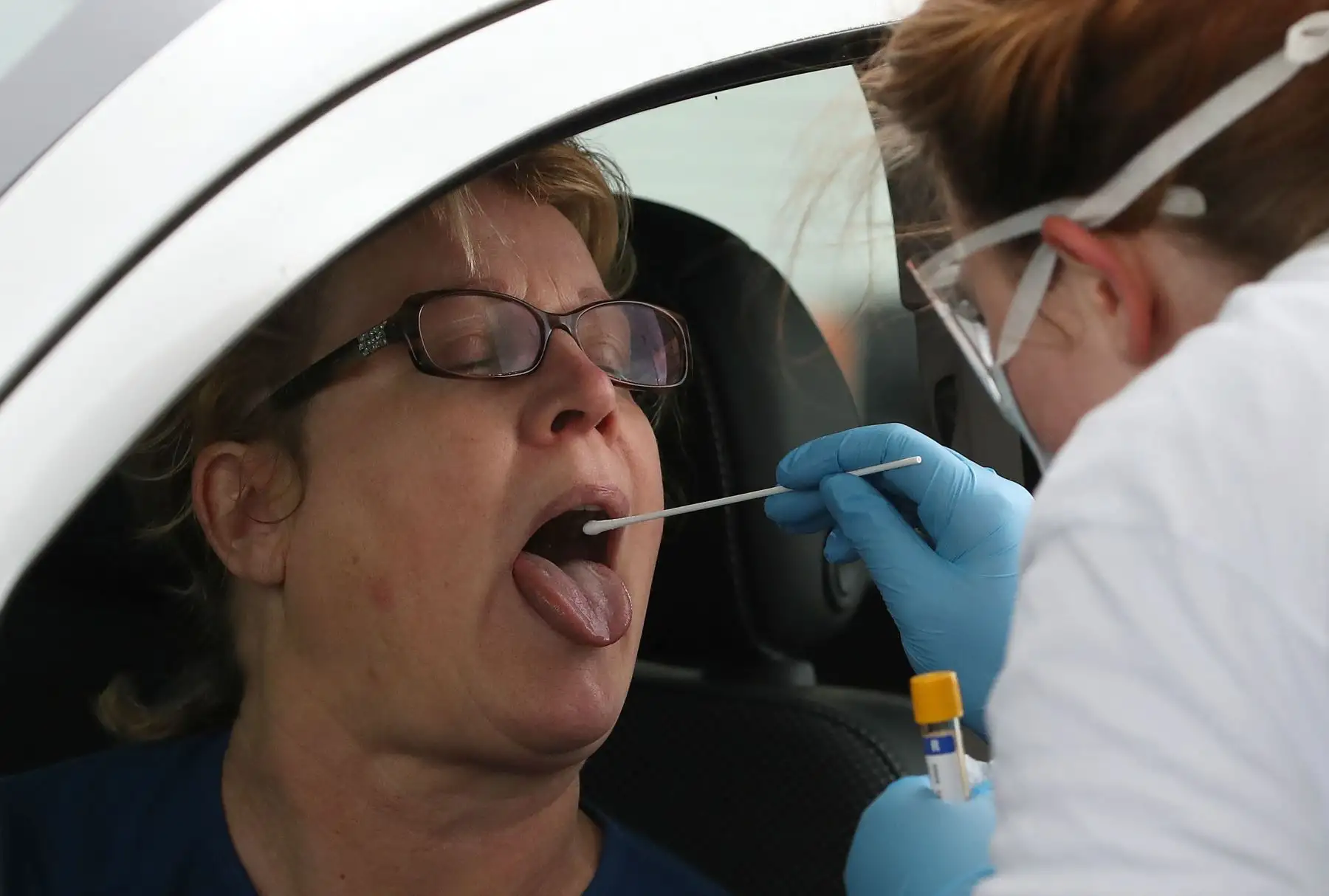 Un trabajador médico realiza el test a un trabajador para el nuevo coronavirus Covid-19 en un centro de pruebas de autocine en el aeropuerto de Glasgow. Foto: AFP