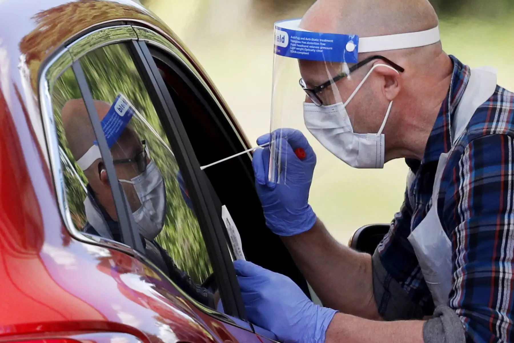 Un trabajador médico toma un hisopo para detectar el nuevo coronavirus COVID-19 de un visitante a un centro de pruebas de manejo en el Chessington World of Adventures Resort, en Chessington. Foto: AFP