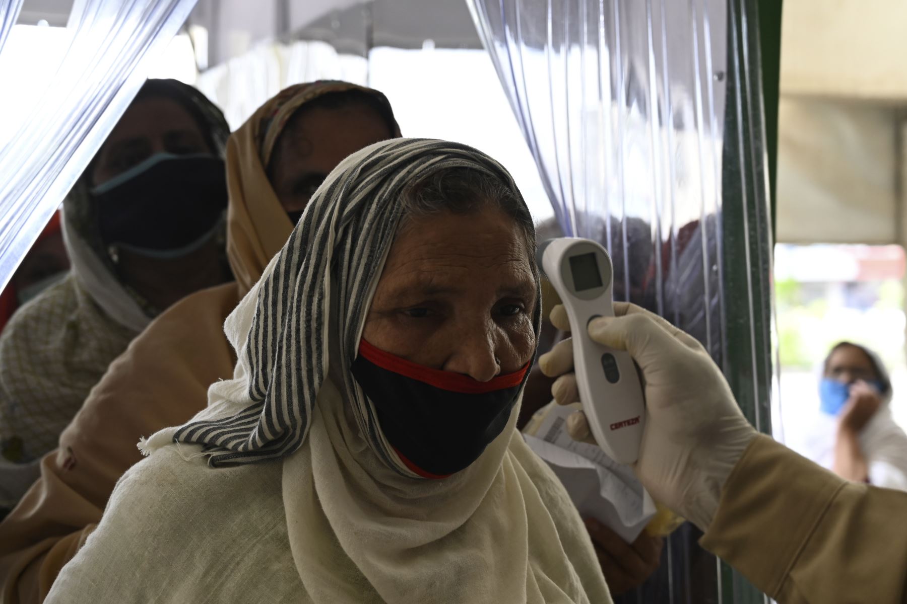 Una paquistaní, cuya etnia tiene 3,29 de veces más riesgo de contraer el covid-19, pasa por un control de temperatura corporal como medida preventiva, en Rawalpindi, Pakistán. Foto: AFP