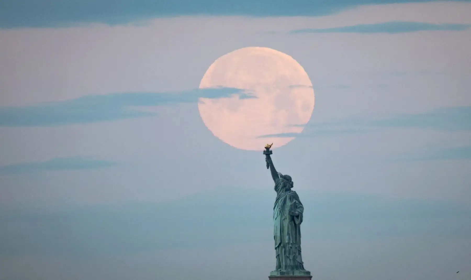 La luna llena de mayo, conocida como la luna llena de flores y es la última superluna del año, se encuentra detrás de la Estatua de la Libertad, en la ciudad de Nueva York.Foto:AFP