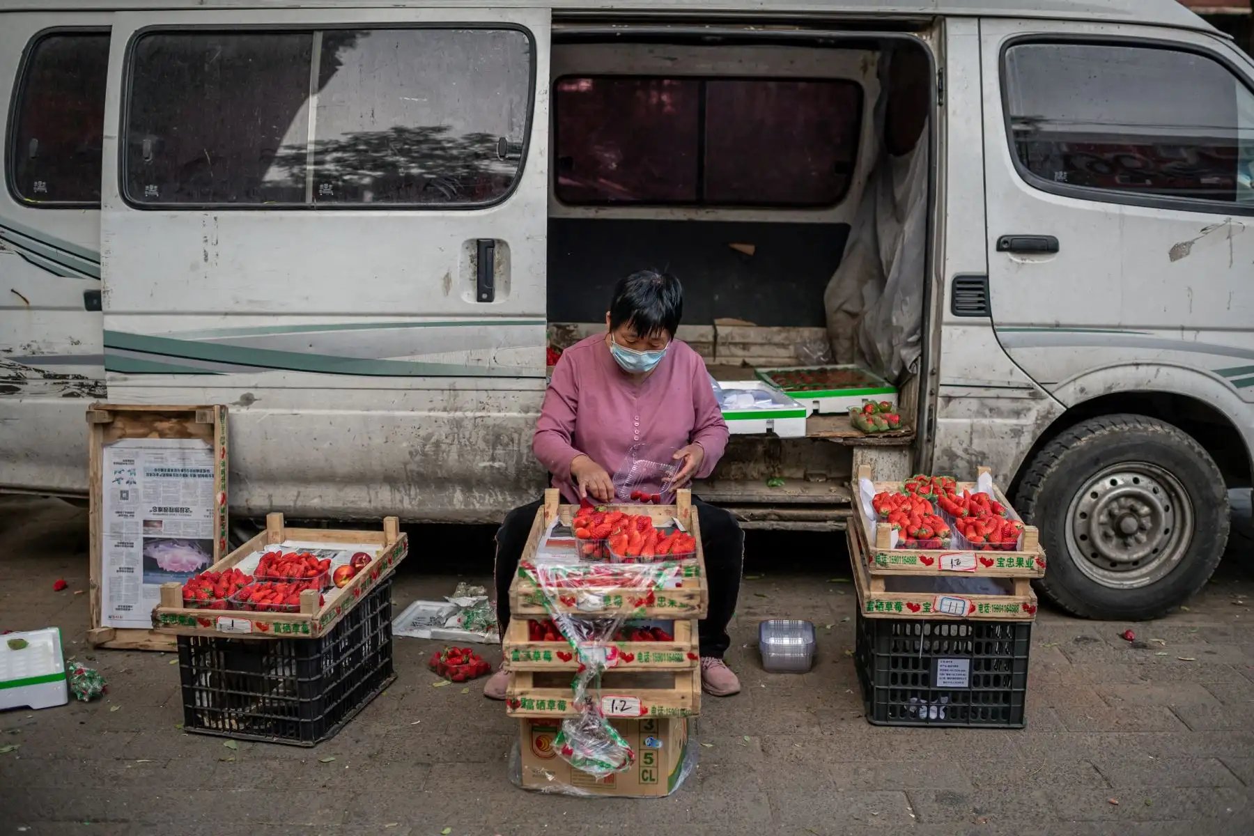 Un vendedora, que usa una máscara facial como medida preventiva contra el coronavirus COVID-19, vende fresas en una calle de Beijing. Foto: AFP