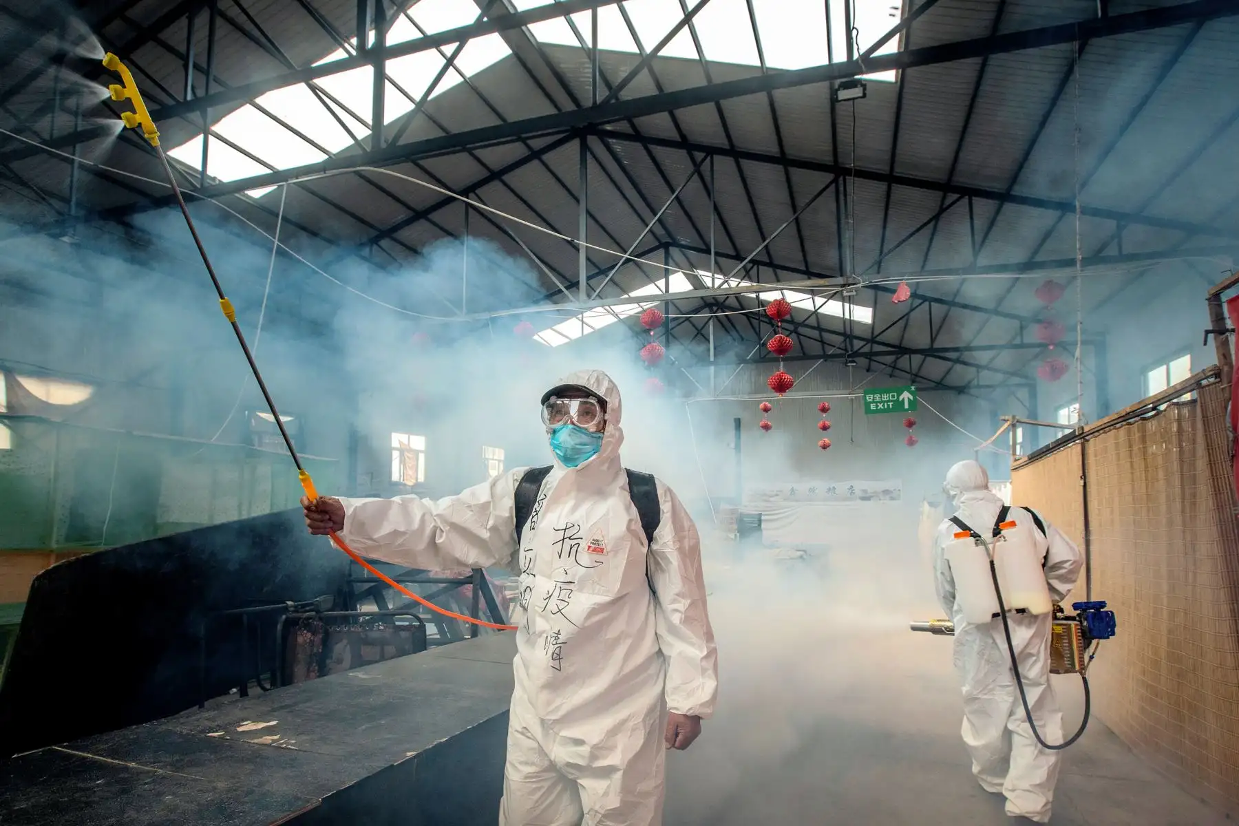 Esta foto tomada muestra a voluntarios rociando desinfectante en un mercado como medida preventiva contra el coronavirus COVID-19. Foto: AFP