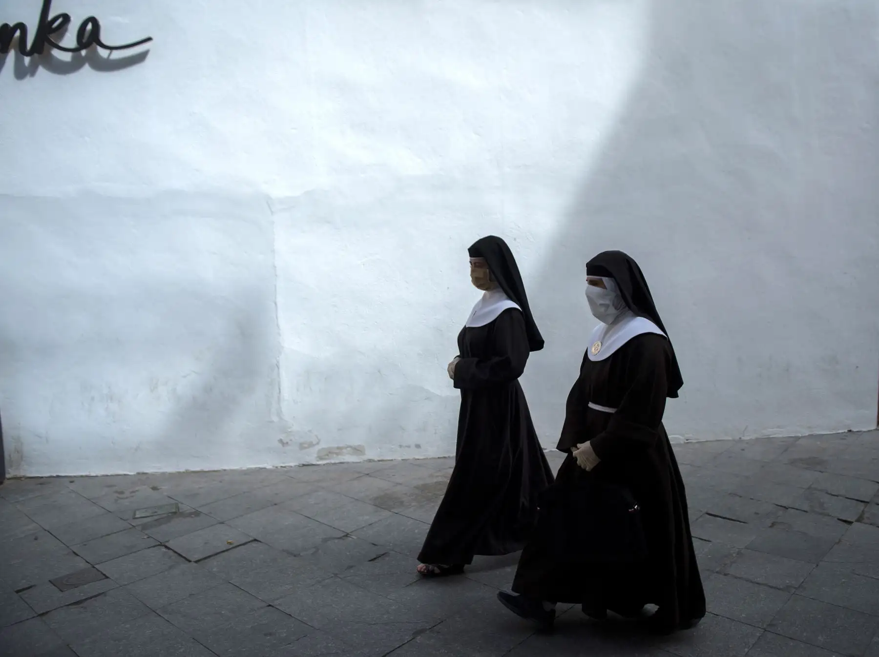 Dos monjas con máscara facial caminan por una calle de Sevilla. Foto: AFP