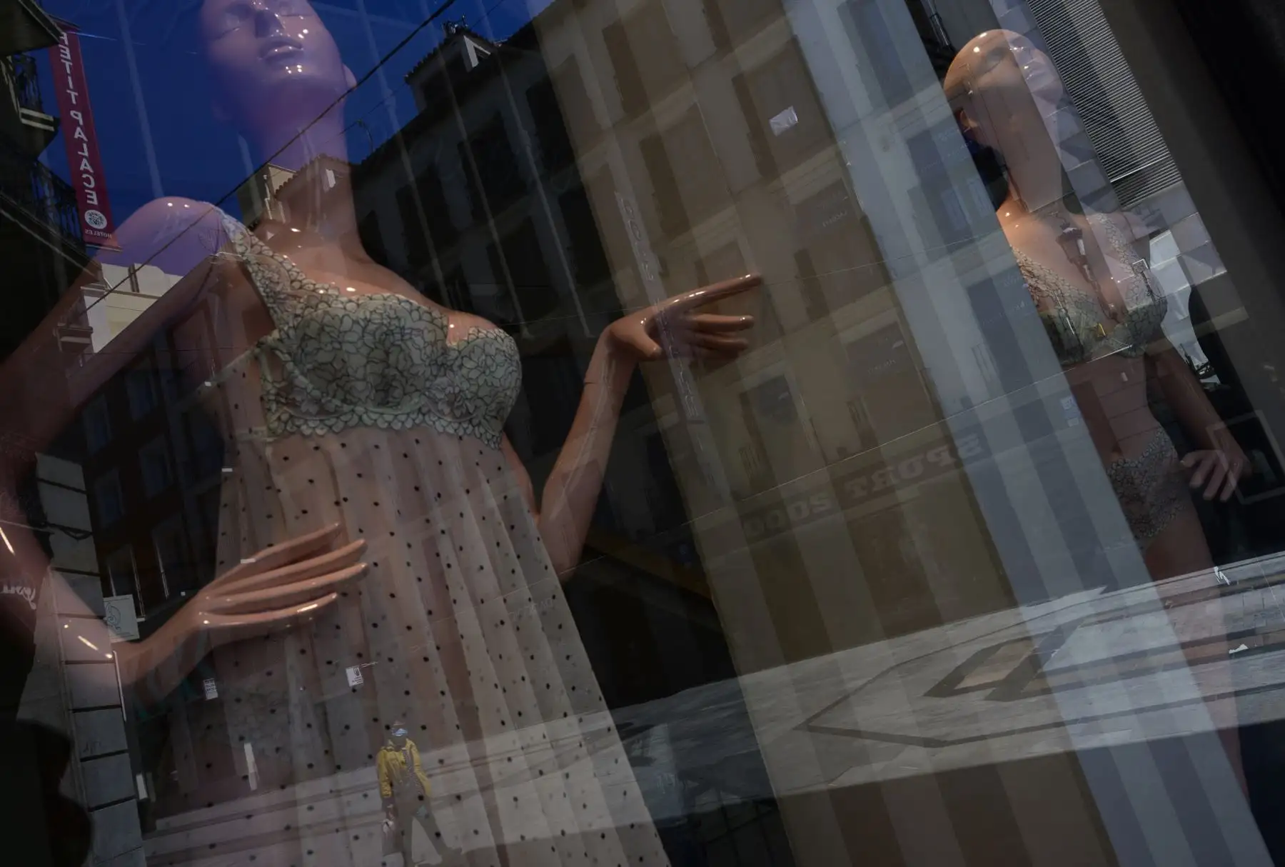Un hombre con una máscara facial se refleja en la ventana de una tienda en el centro de Madrid. Foto. AFP