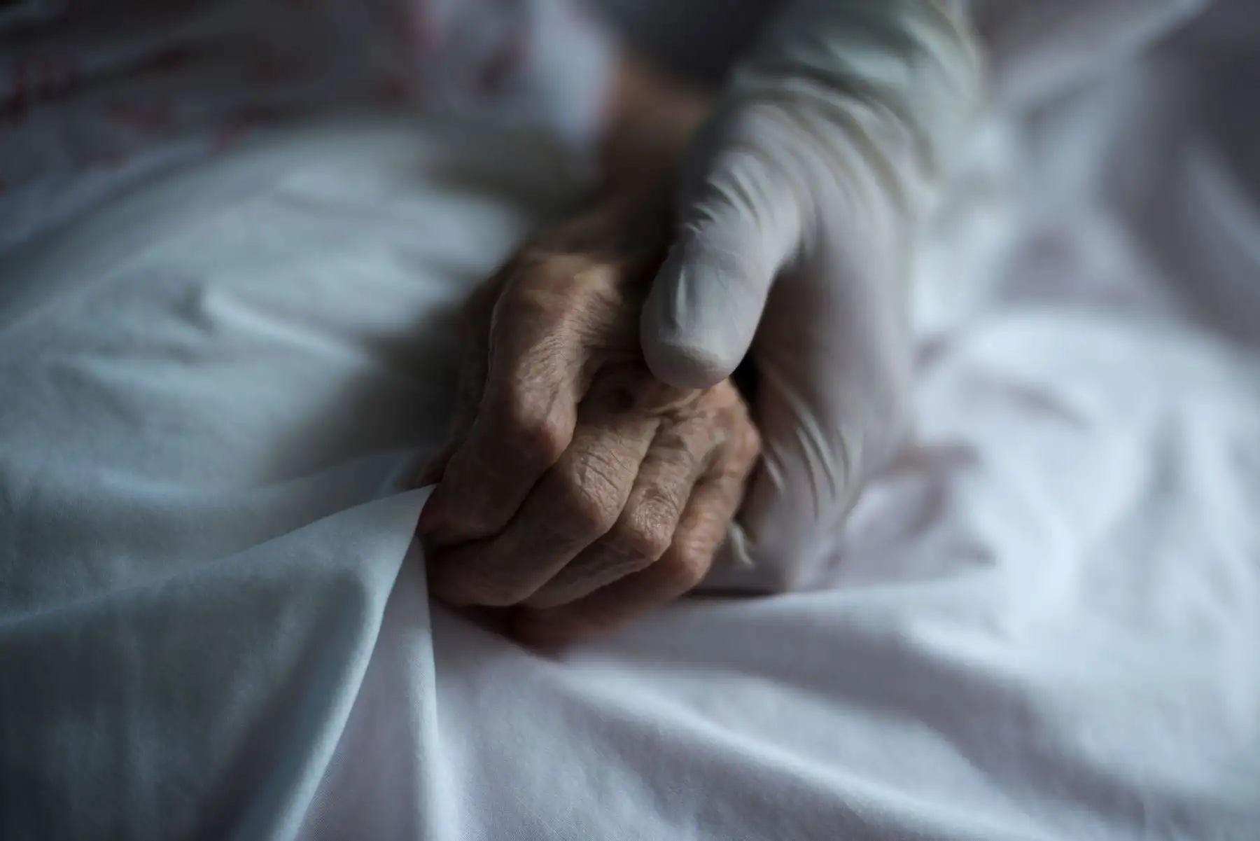 En la imagen, una trabajadora de la residencia de Celanova sujeta la mano de una residente. Foto: EFE