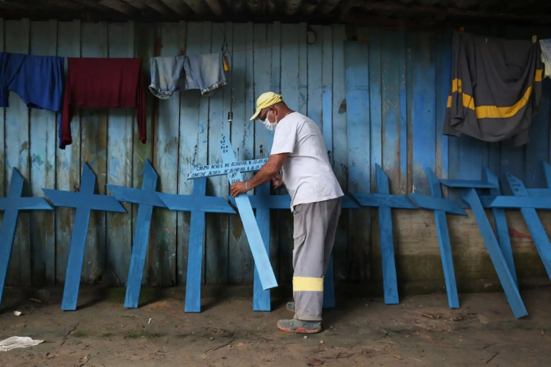 Ulises coloca cruces de manera en la pared de su vivienda las cuales llevará al cementerio Nossa Senhora en Manaus, Brasil. Foto: AFP