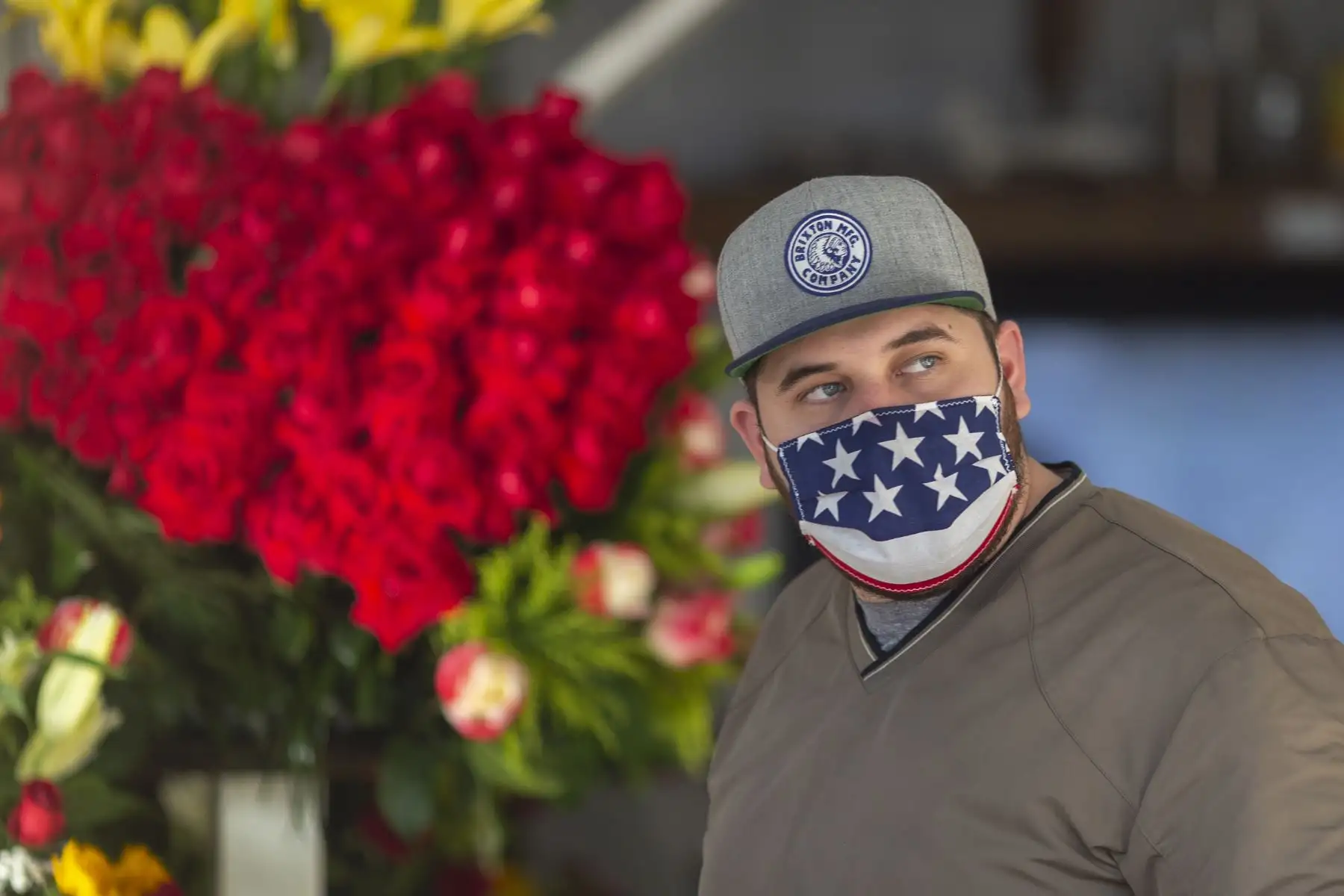 Un hombre camina con una mascarilla patriótica mientras las empresas en el distrito de las flores en Skid Row reabran sus negocios. Foto: AFP