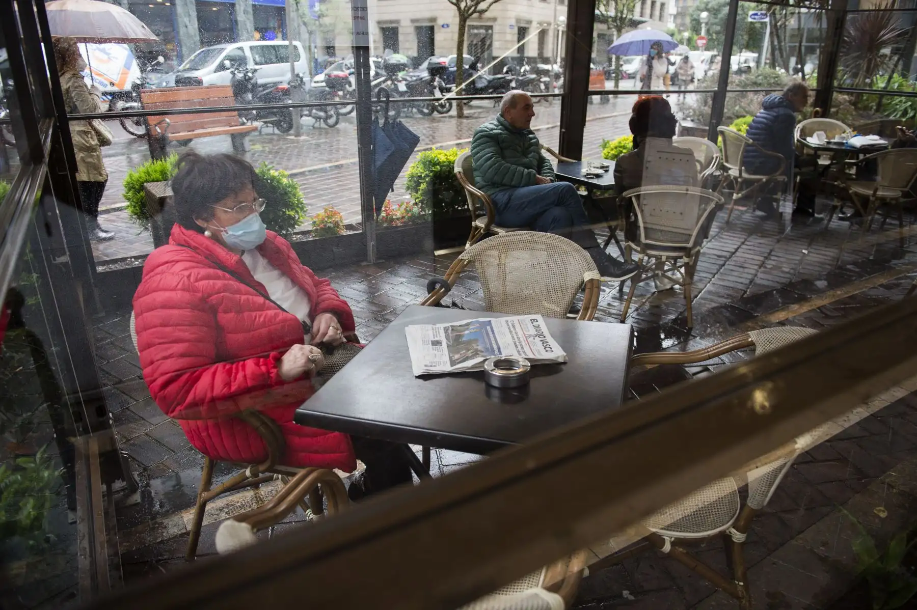 Una mujer que llevaba una máscara se sienta en una cafetería en la ciudad vasca española de San Sebastián. Foto: AFP