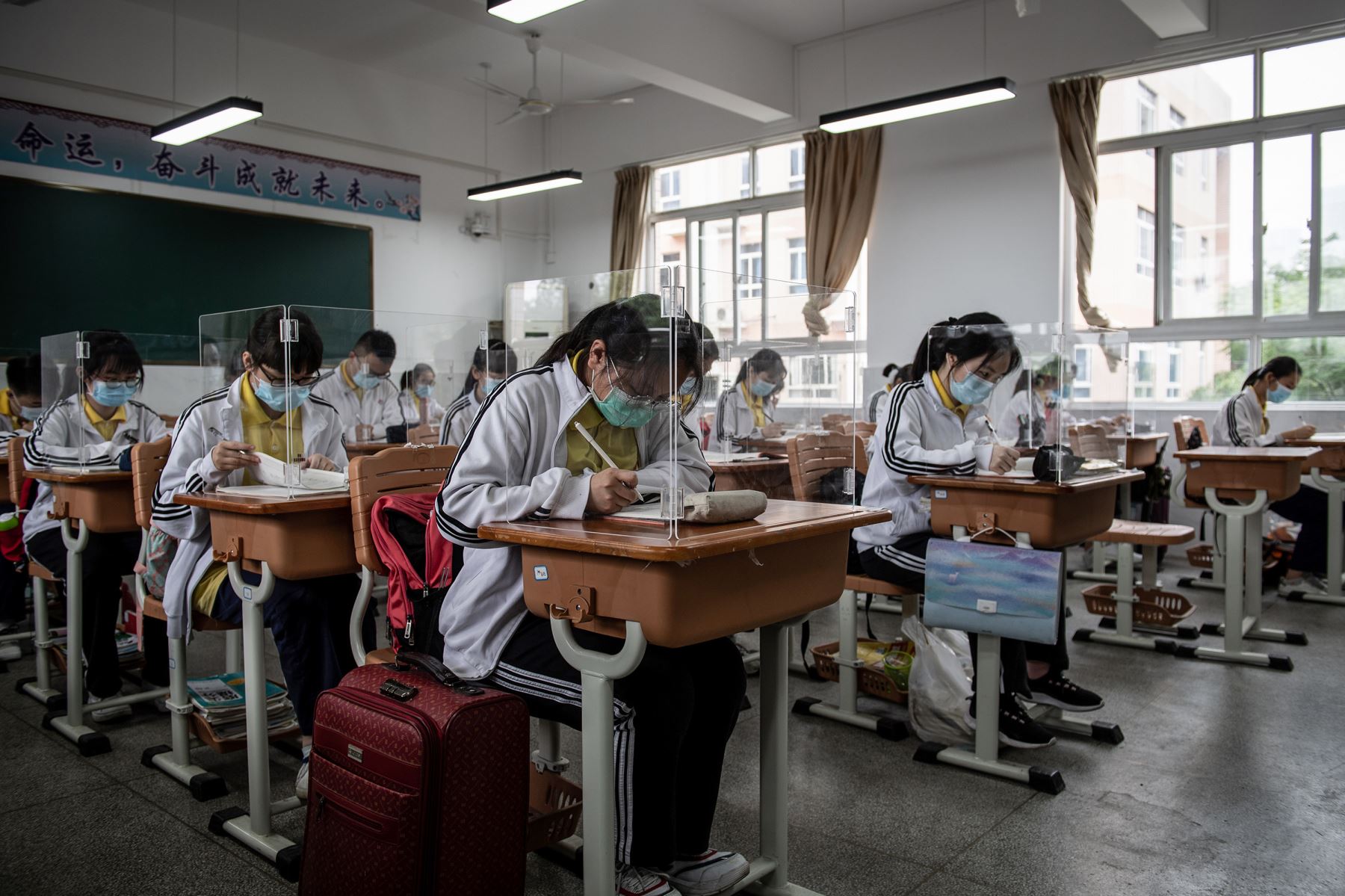 Los estudiantes de último año de secundaria estudian con separadores de plástico en un aula en Wuhan, en la provincia central china de Hubei. Foto: AFP