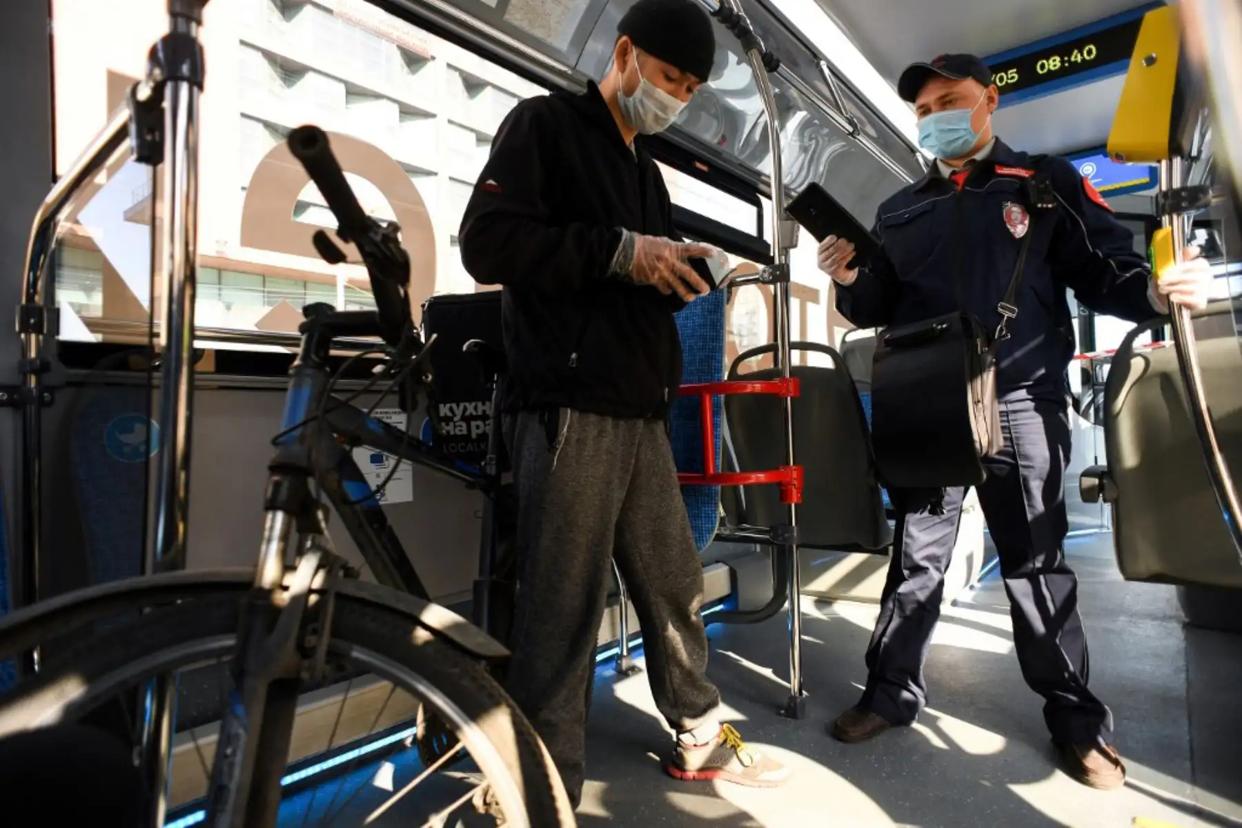 Un inspector revisa los documentos de un hombre que viajaba en un autobús eléctrico el primer día de uso obligatorio de máscaras y guantes en el transporte público de Moscú, en Moscú el 12 de mayo de 2020, en medio de la pandemia de coronavirus. (Foto por Kirill KUDRYAVTSEV / AFP)