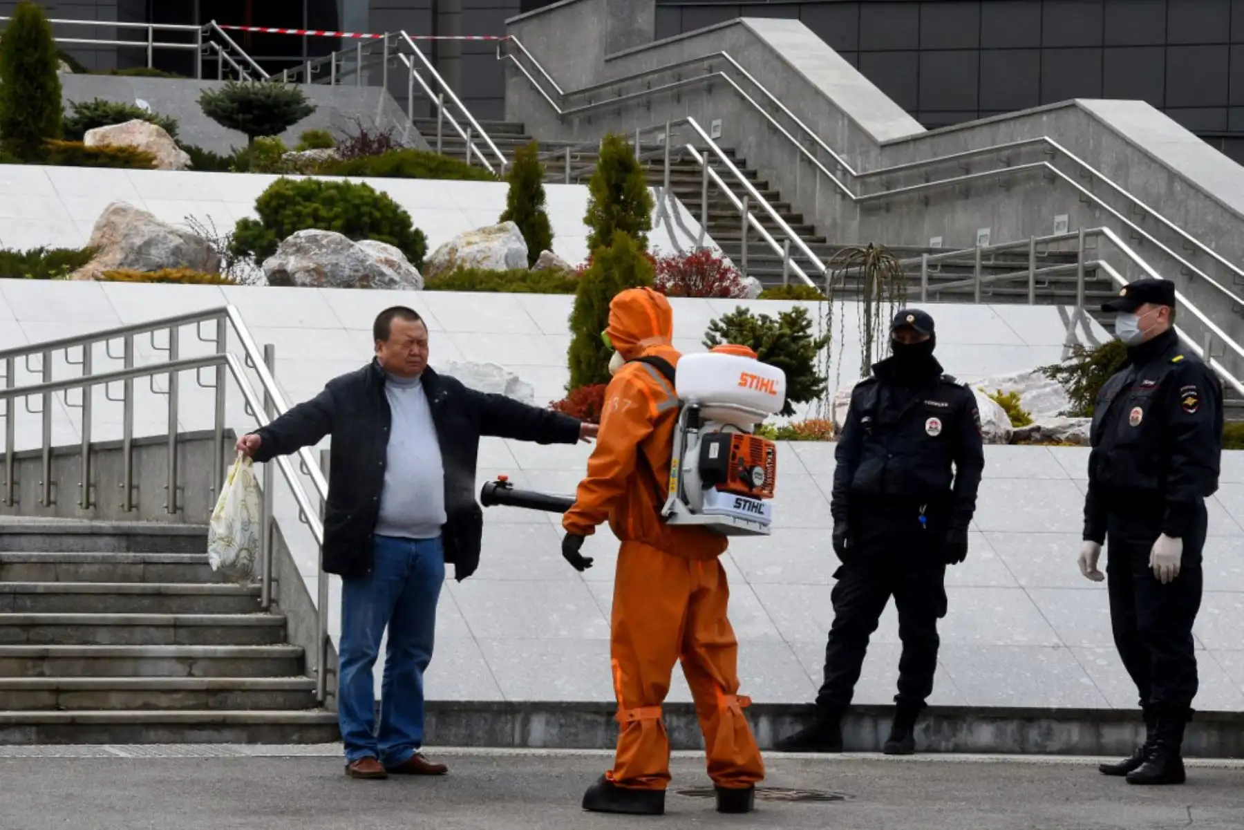 Personal de emergencias con equipo de protección desinfectante en aerosol aplica sobre un hombre en el lugar del incendio en el hospital Saint George en San Petersburgo el 12 de mayo de 2020. 

(Foto por OLGA MALTSEVA / AFP)