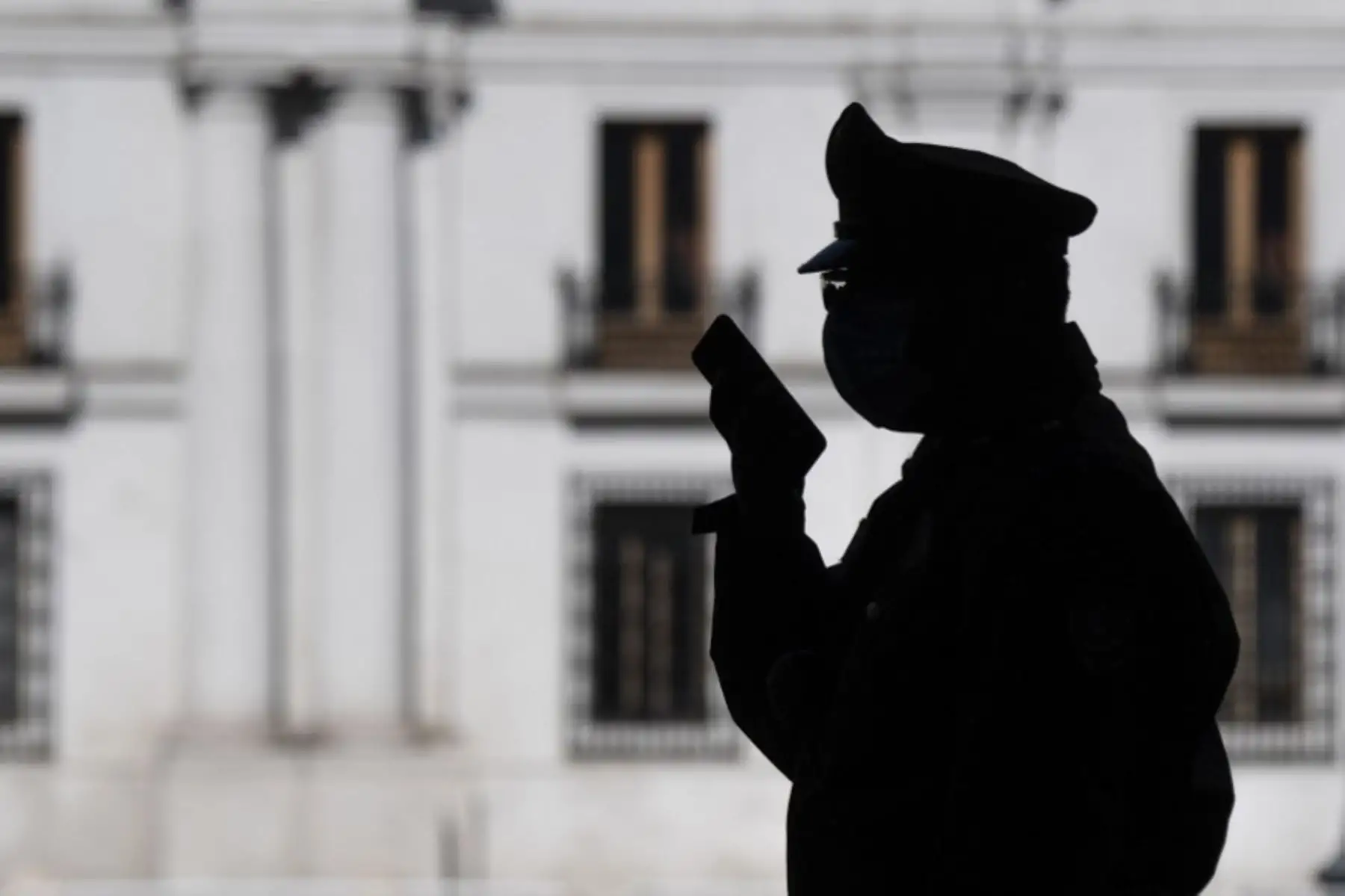 Un policía habla usa su teléfono móvil mientras está de guardia fuera del palacio presidencial de La Moneda en Santiago, el 13 de mayo de 2020, en medio de la nueva pandemia de coronavirus.

(Foto por Martin BERNETTI / AFP)